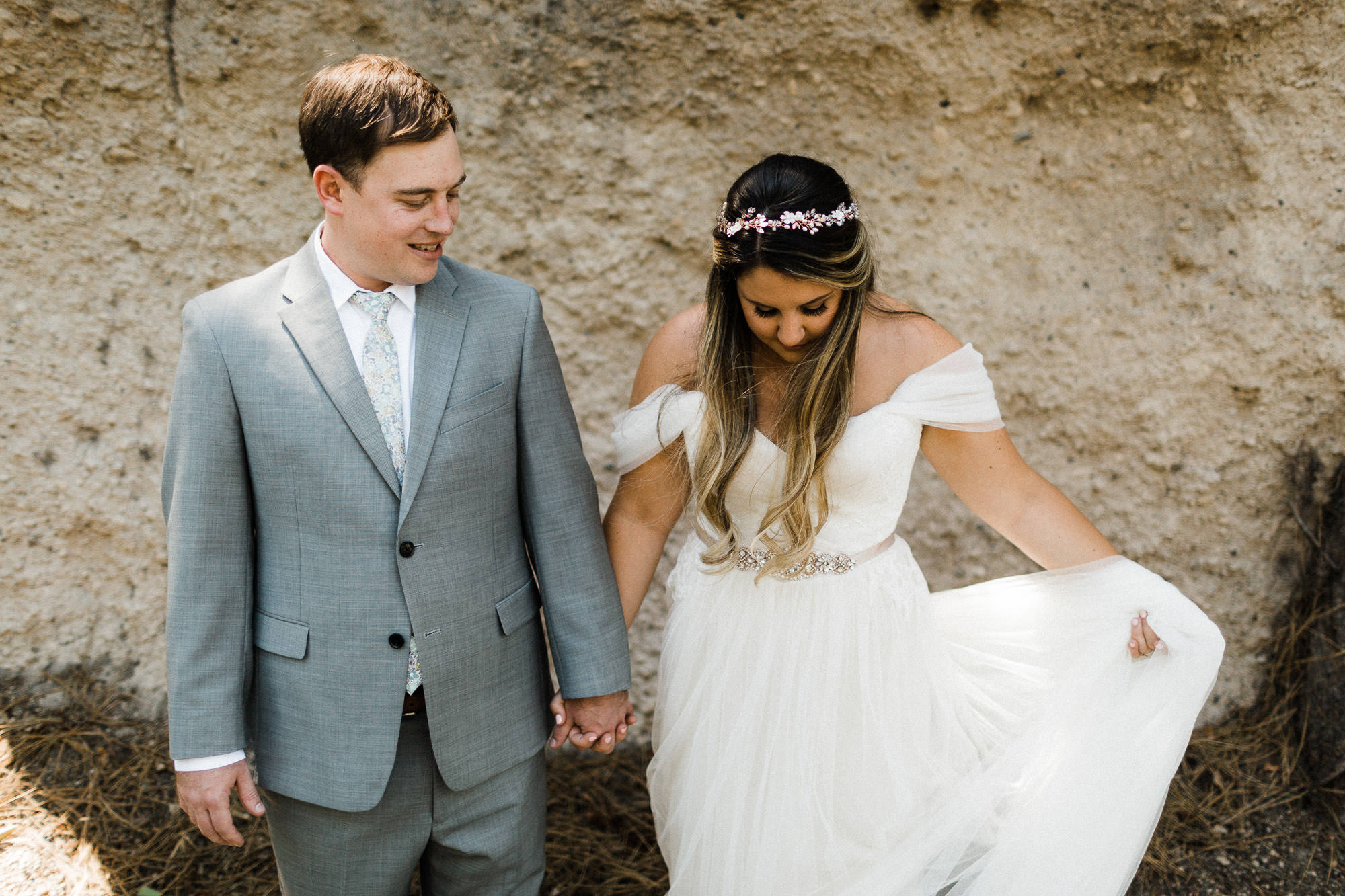 Bride and groom hold hands in front of rock at Broken Top Club in Bend, Oregon
