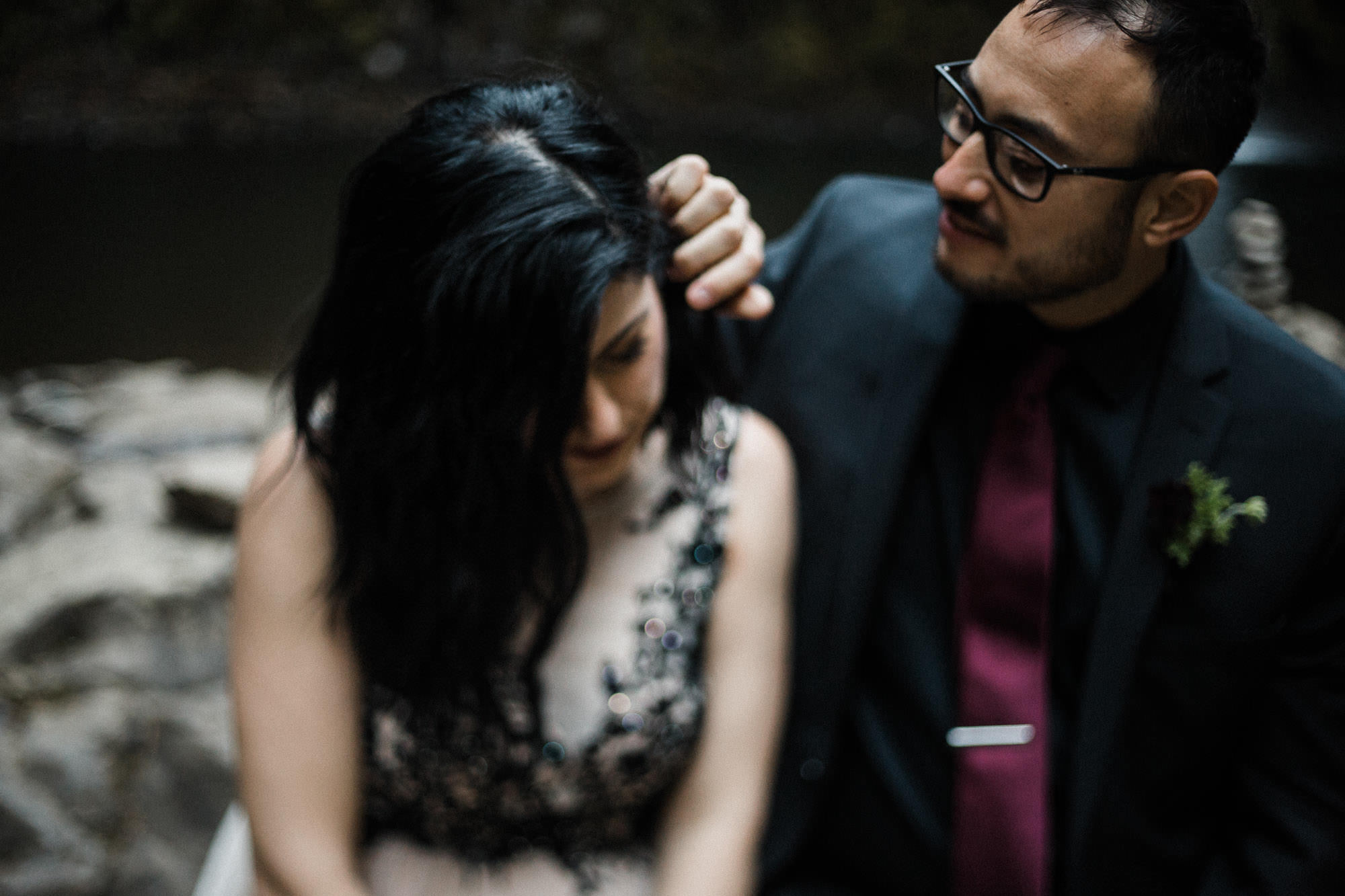 Groom brushes hair from his bride's face at Abiqua Falls, Oregon
