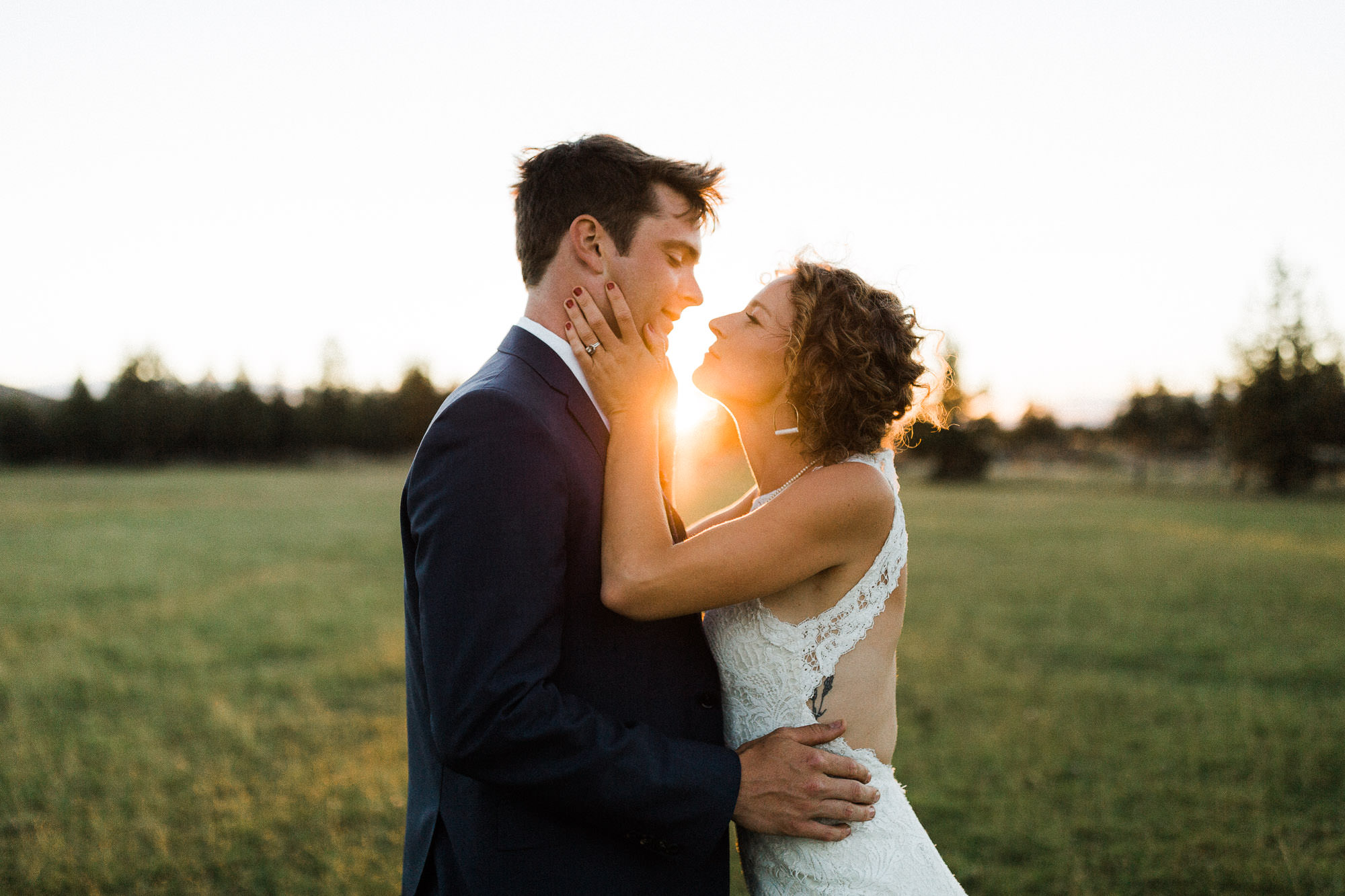 Bride holds grooms face in her hands at sunset in Redmond, Oregon