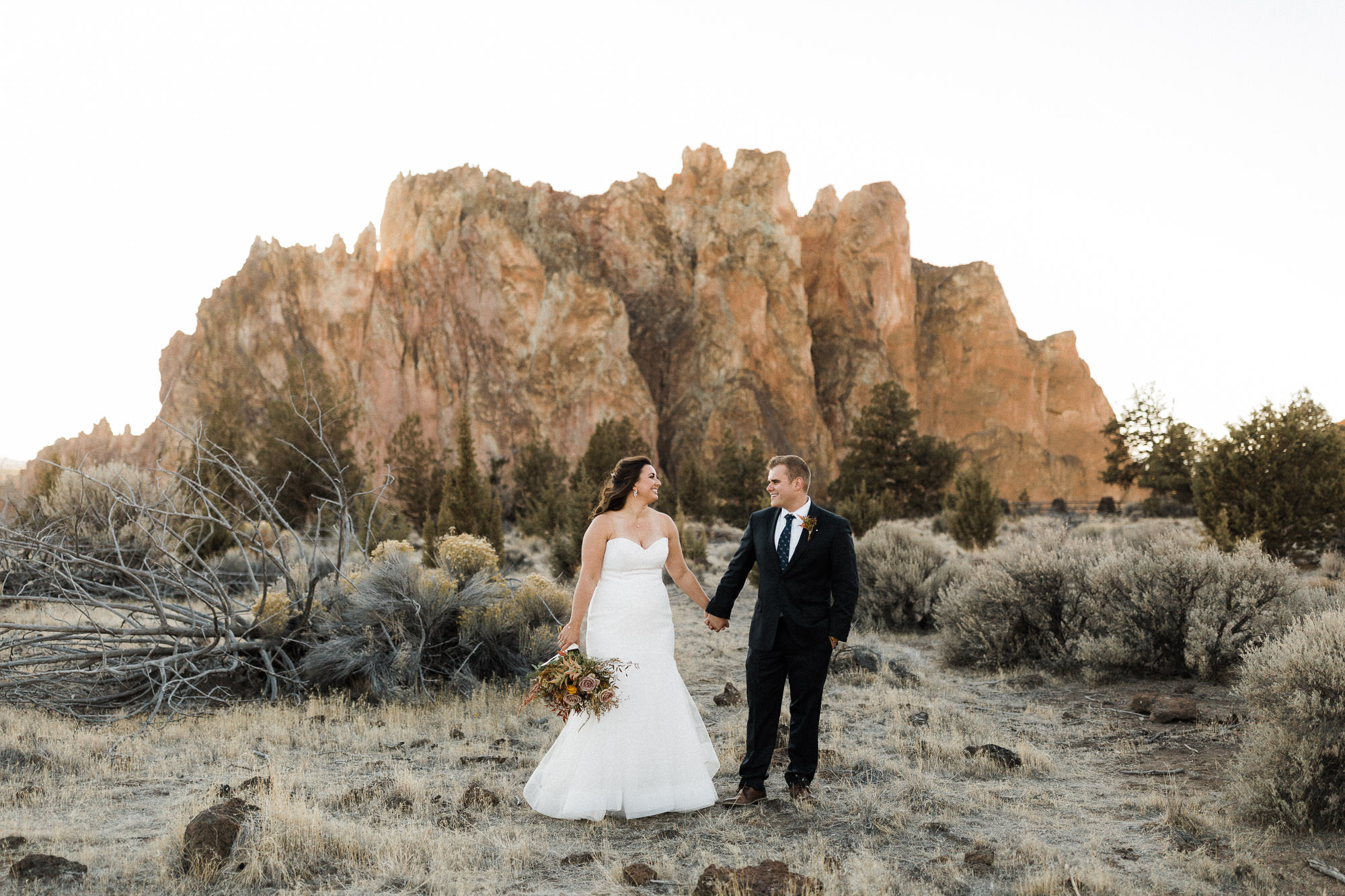 Bride and groom hold hands at Smith Rock State Park in Oregon