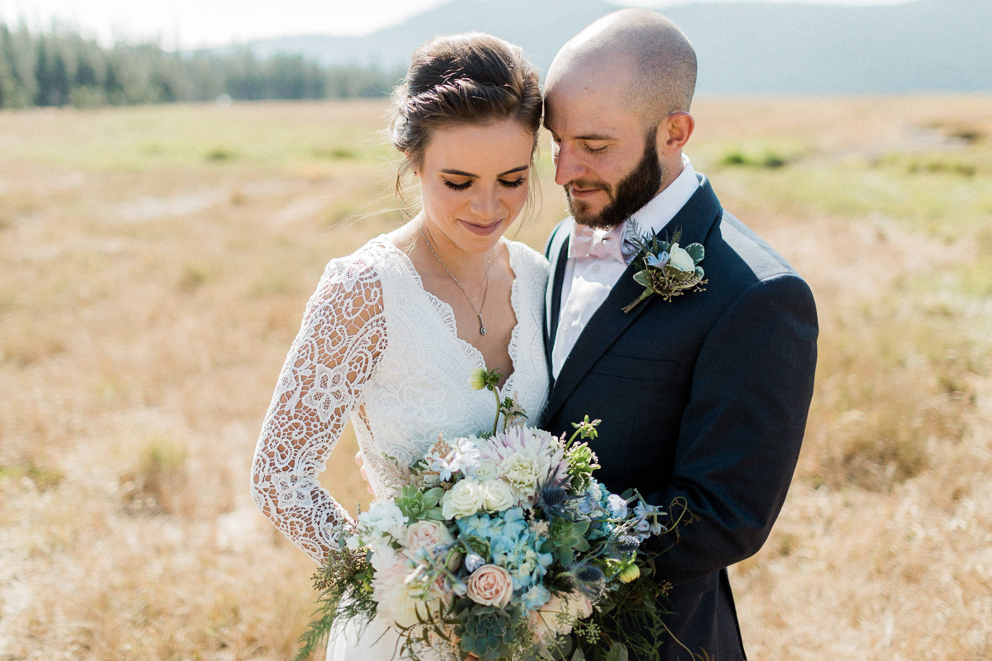 Bride and groom embrace in a field at Sparks Lake near Bend, Oregon