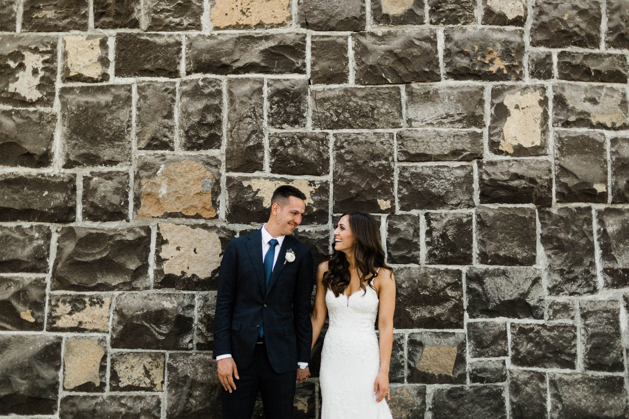 Bride and groom hold hands in front of chimney at Sunriver Resort Great Hall