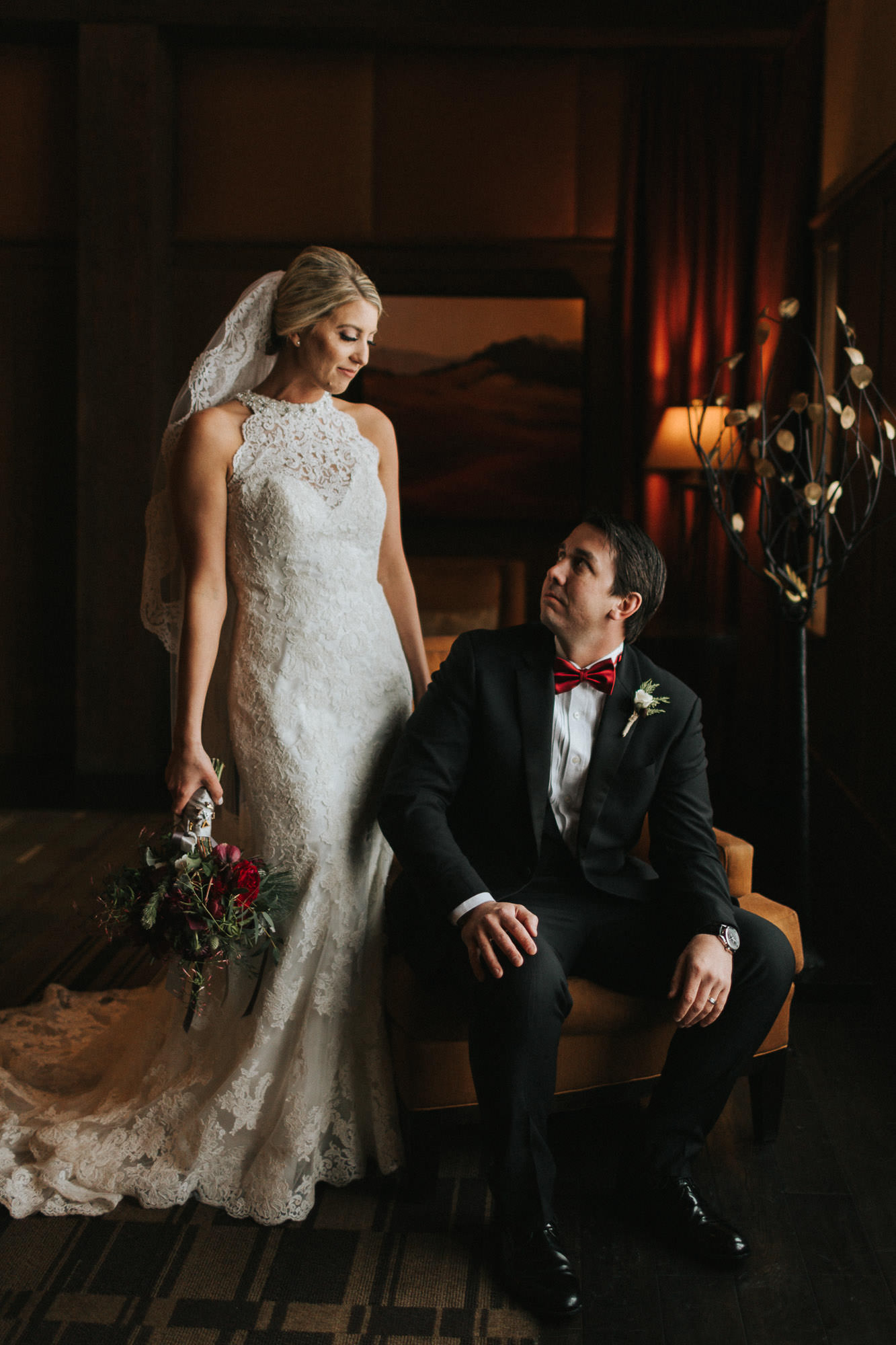 Standing bride makes eye contact with seated groom at Tetherow Resort in Bend, Oregon