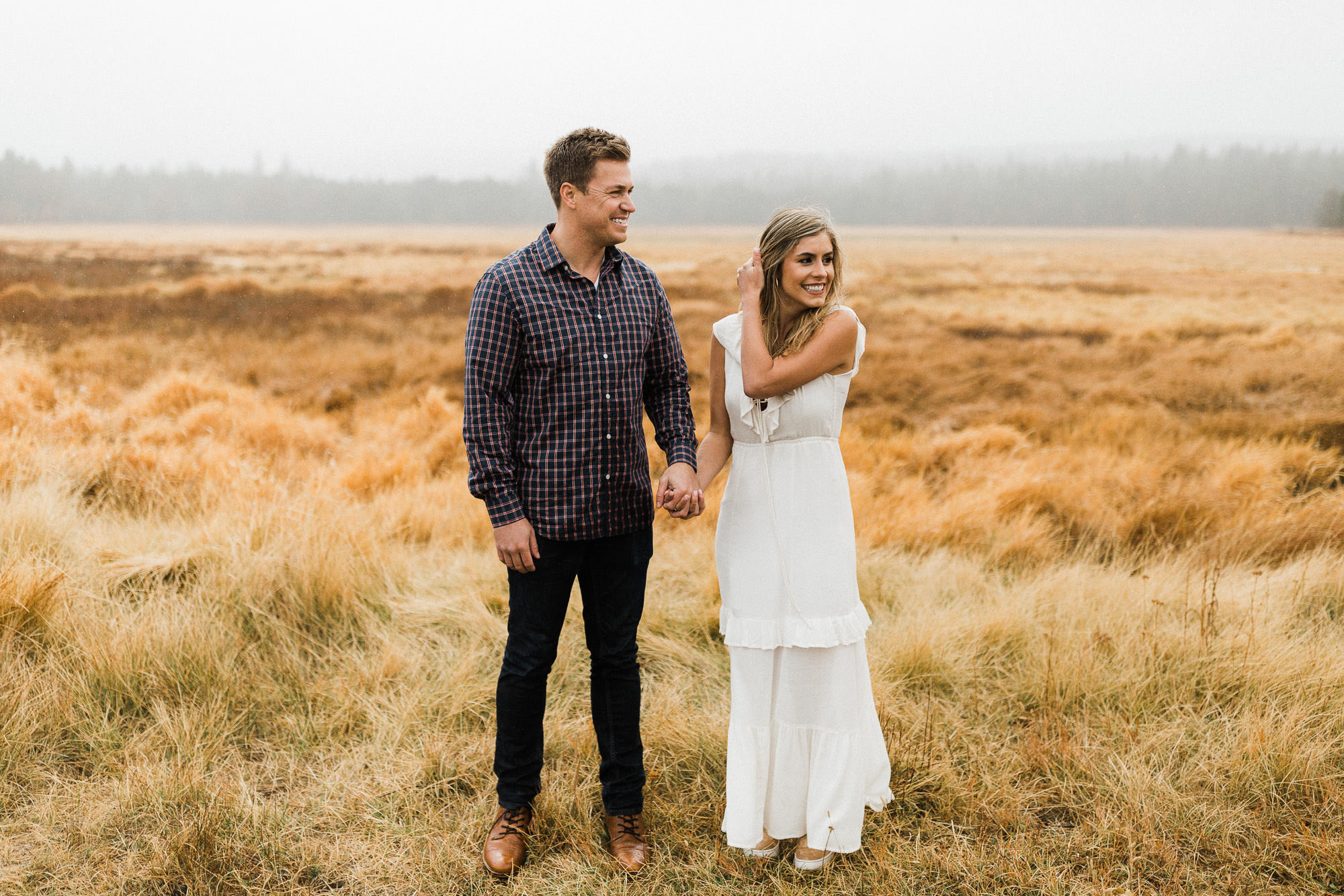 A couple holds hands in a field in Bend, Oregon