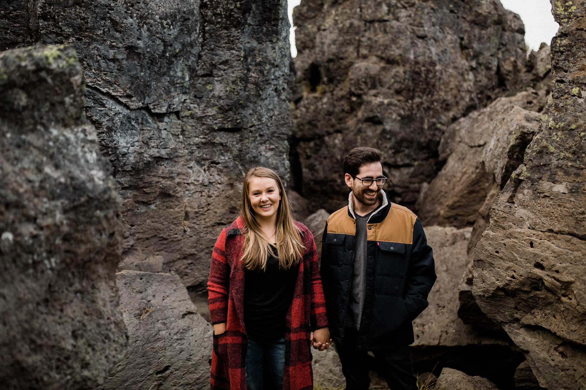 Couple holds hands in front of lava rocks at Sparks Lake, Oregon