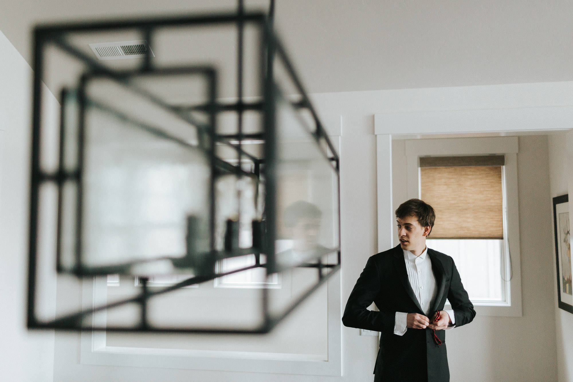 Groomsman buttons his jacket in a house at Tetherow Resort in Bend, Oregon