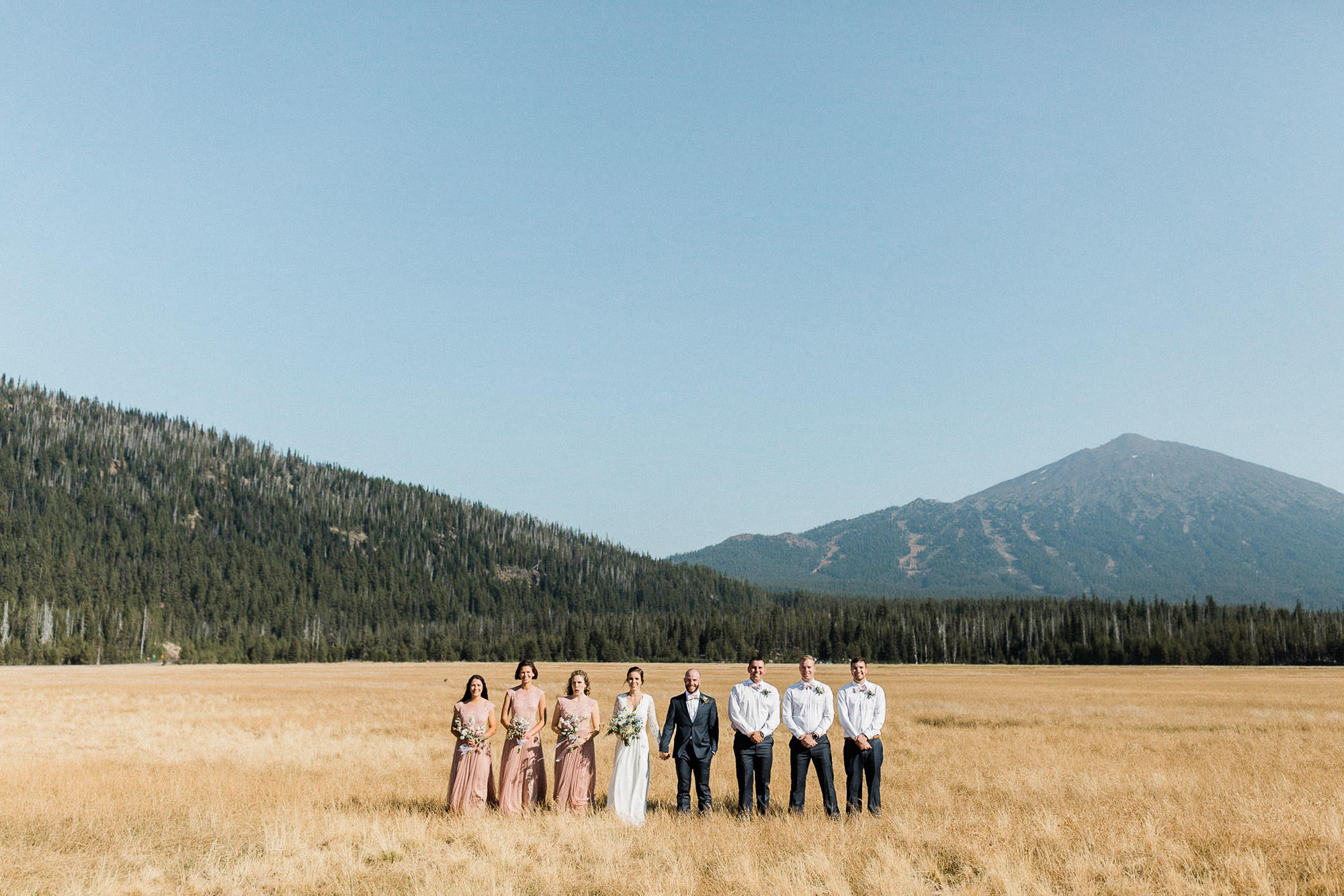 Wedding party stands in a field at Sparks Lake, Oregon