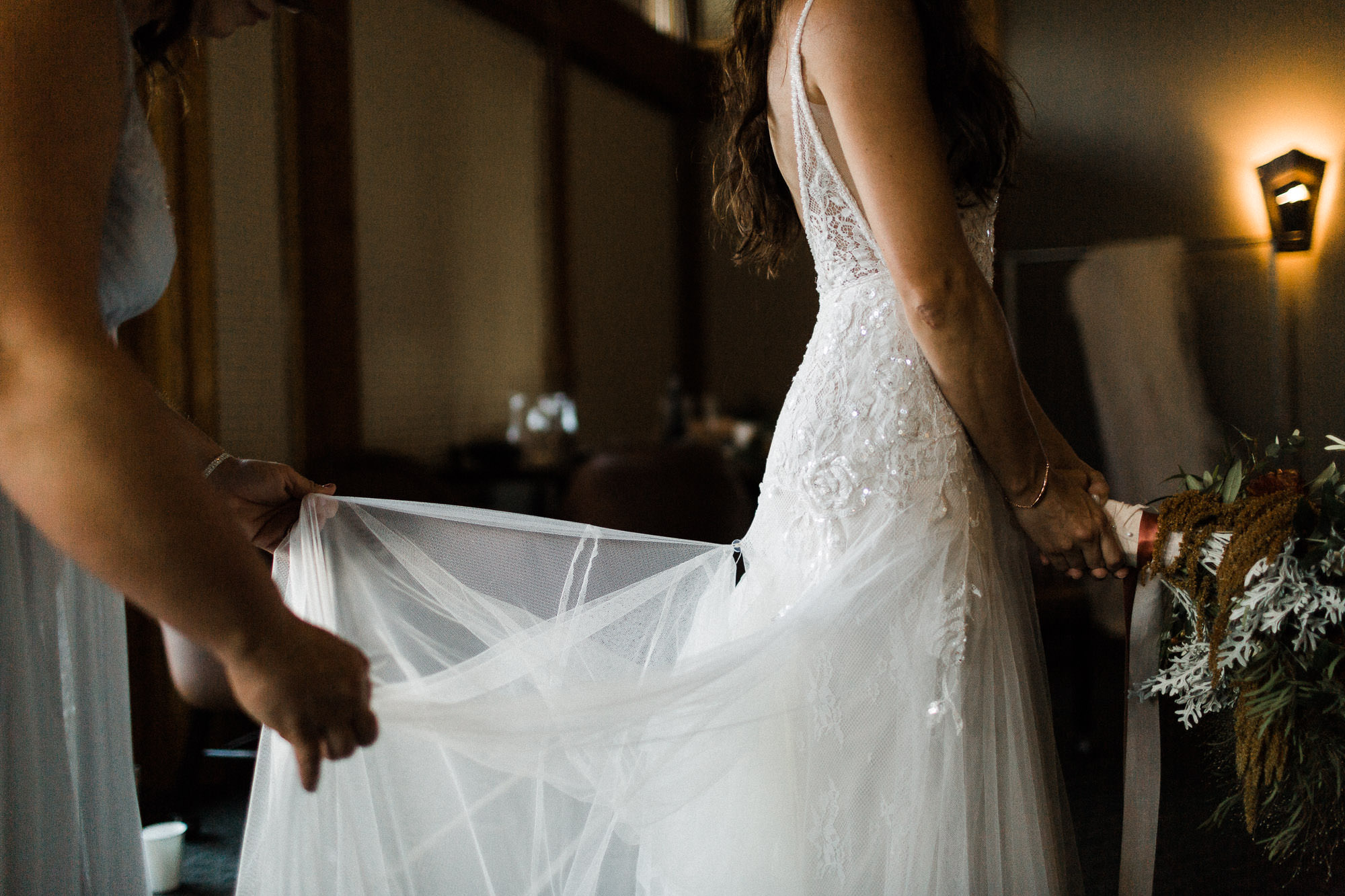 Bridesmaid bustles bride's dress at Broken Top Club in Bend, Oregon
