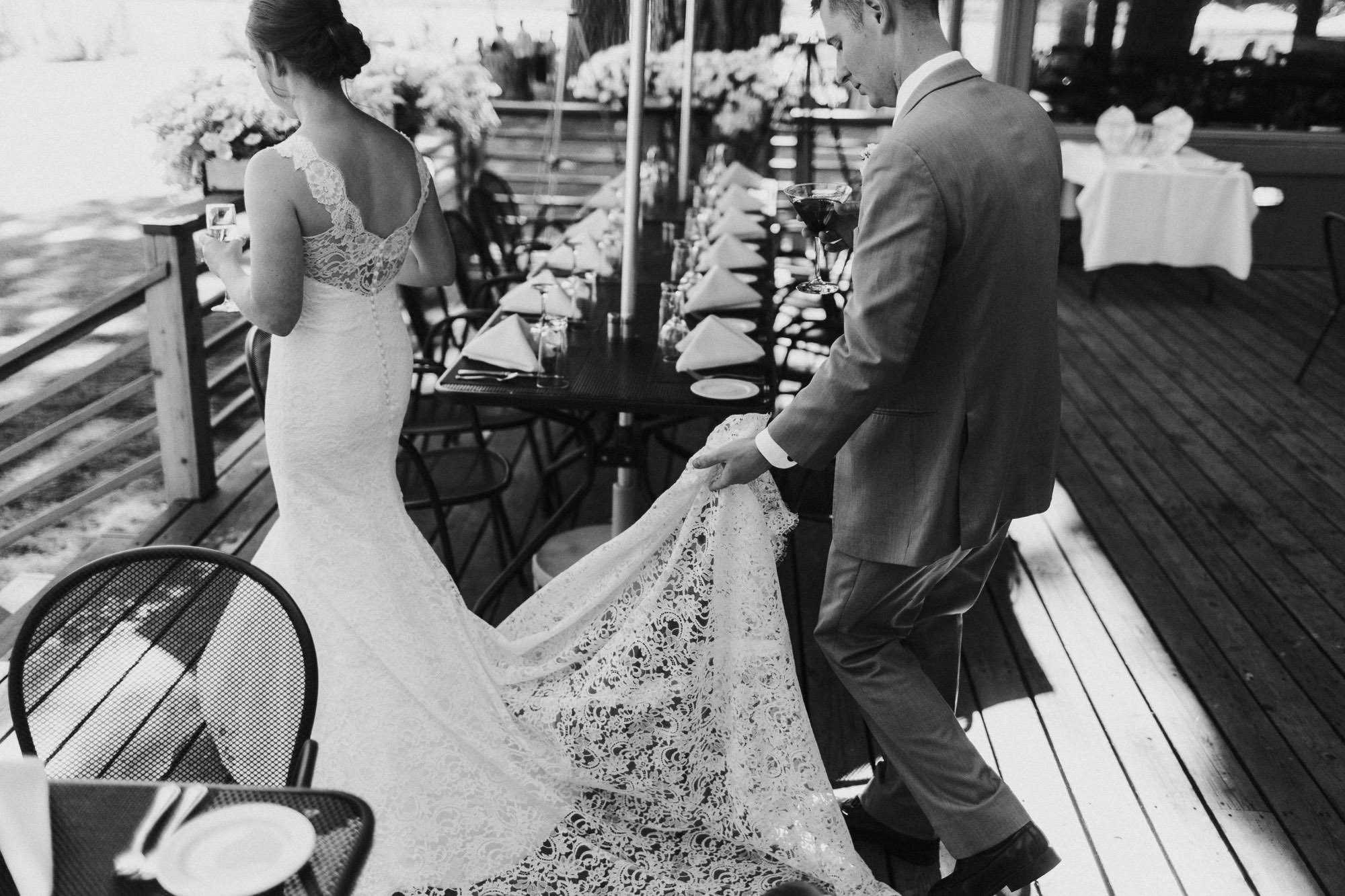 Groom holds the train of the bride's dress as they walk outside at Black Butte Ranch
