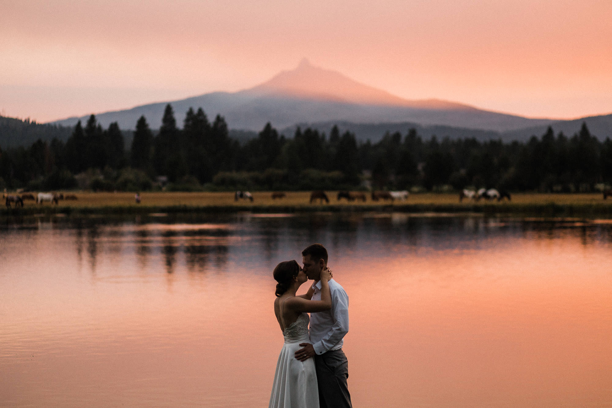 Bride and groom kiss during sunset with Mt. Washington in the background at Black Butte Ranch