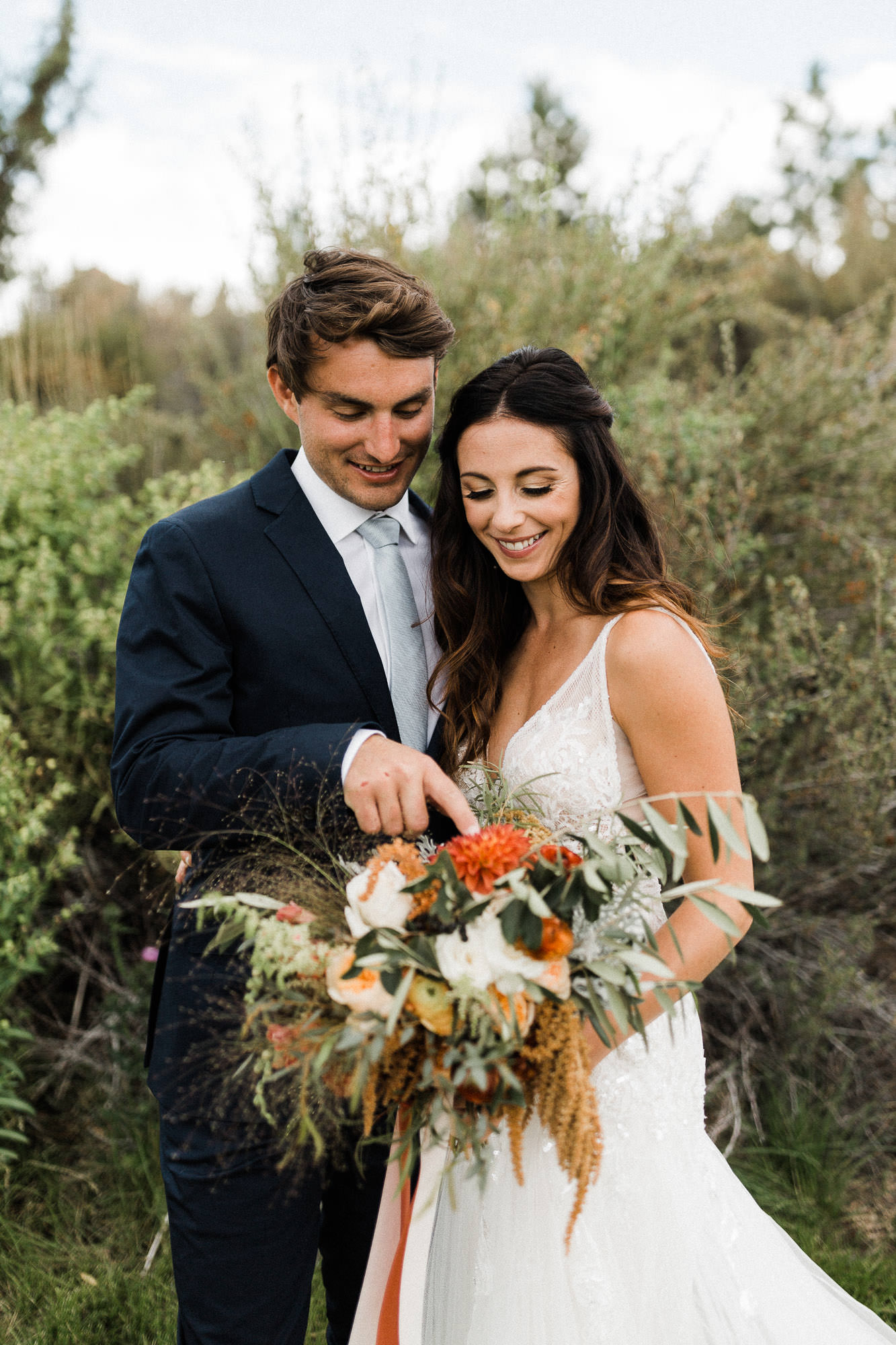 Bride and groom admire bride's bouquet at Broken Top Club in Bend, Oregon
