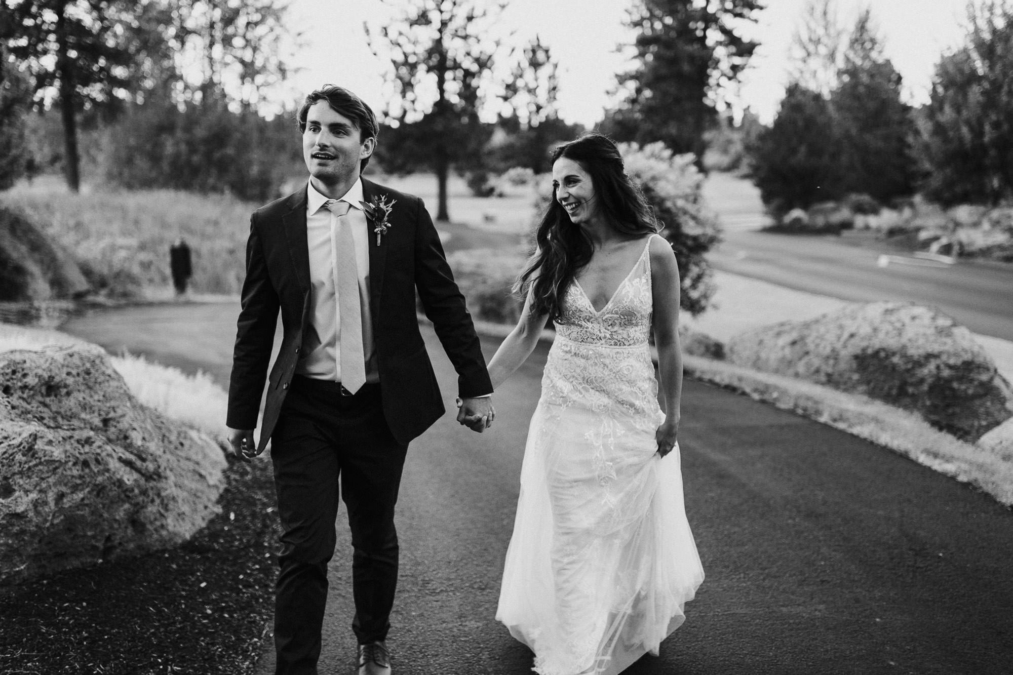 Bride and groom walk and hold hands at Broken Top Club in Bend, Oregon