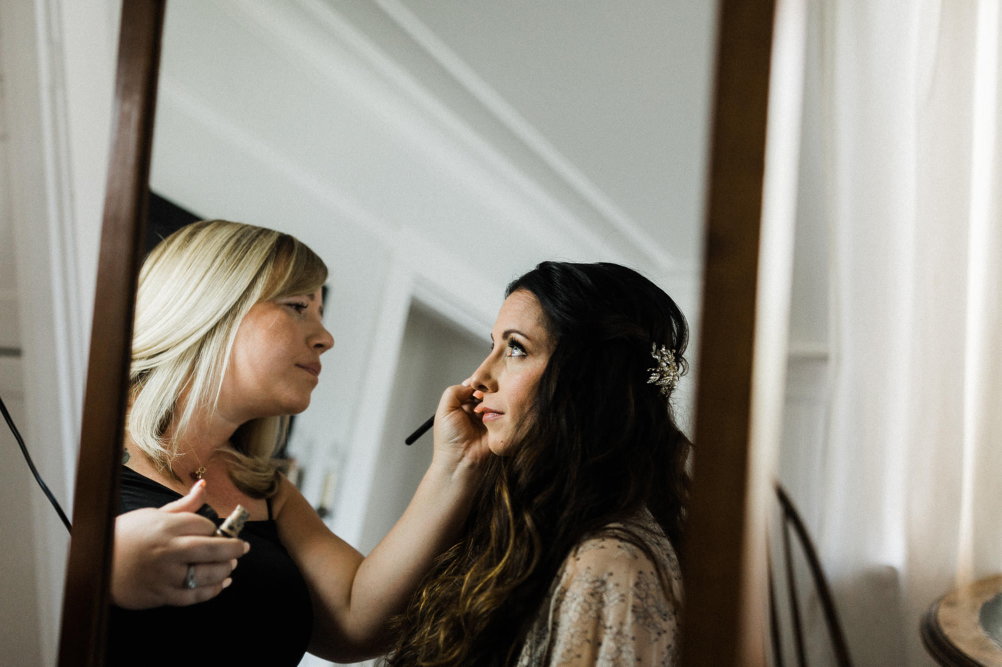 Makeup artist applies eyeliner to bride in a cottage in Bend, Oregon