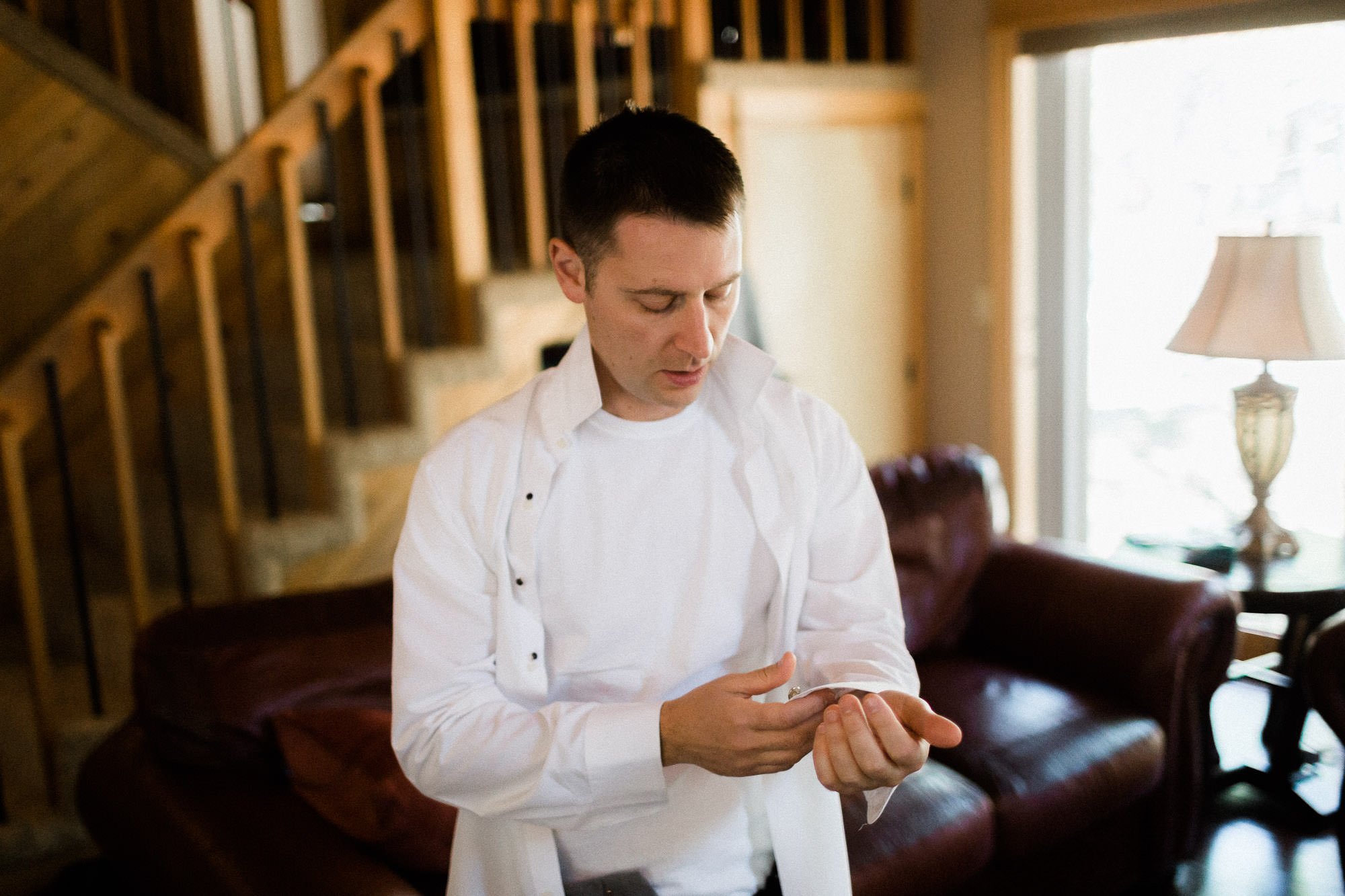 Groom buttons his shirt cuffs at Black Butte Ranch in Oregon