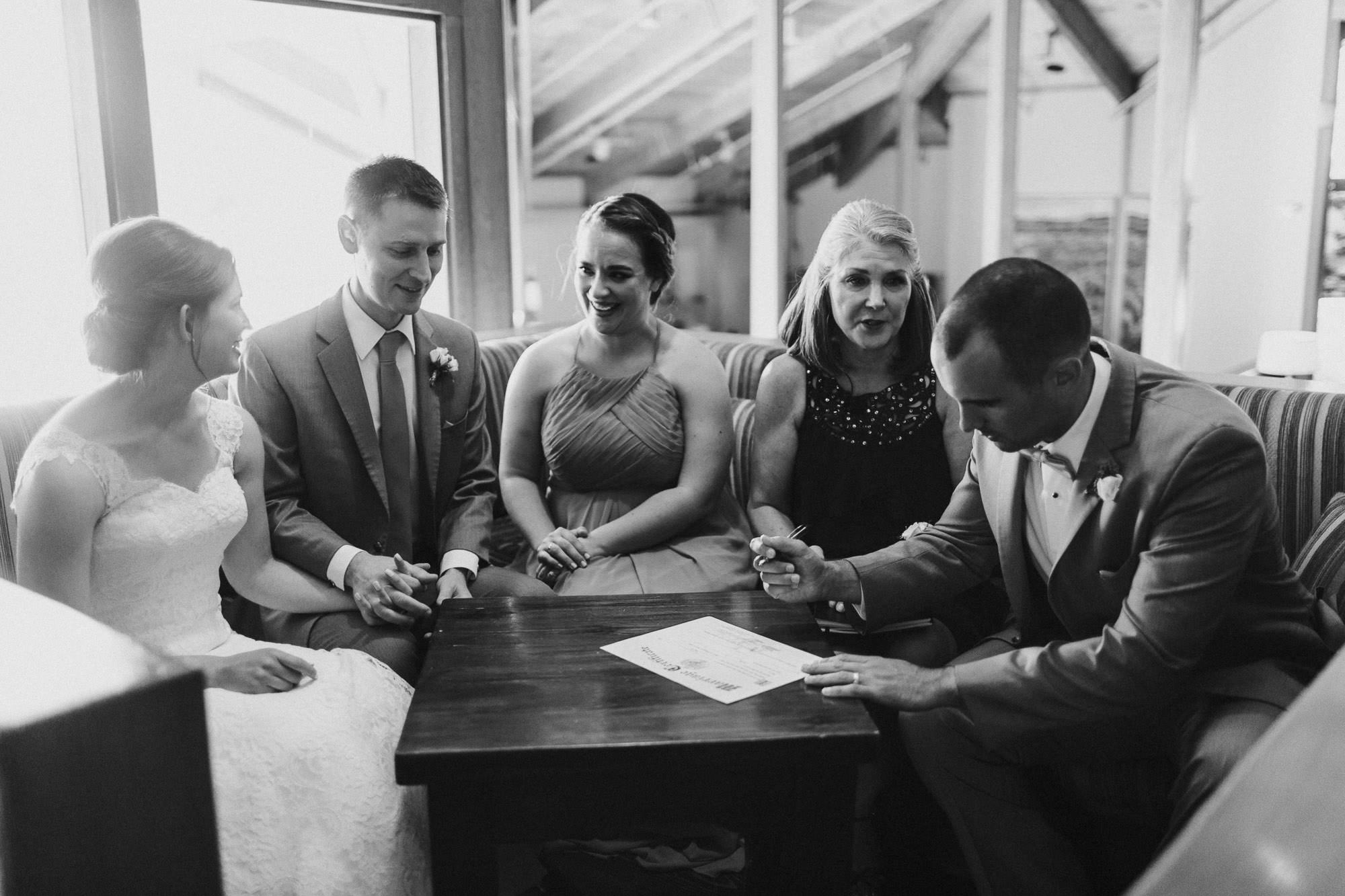 Best man signs the marriage license as the rest of the wedding party looks on