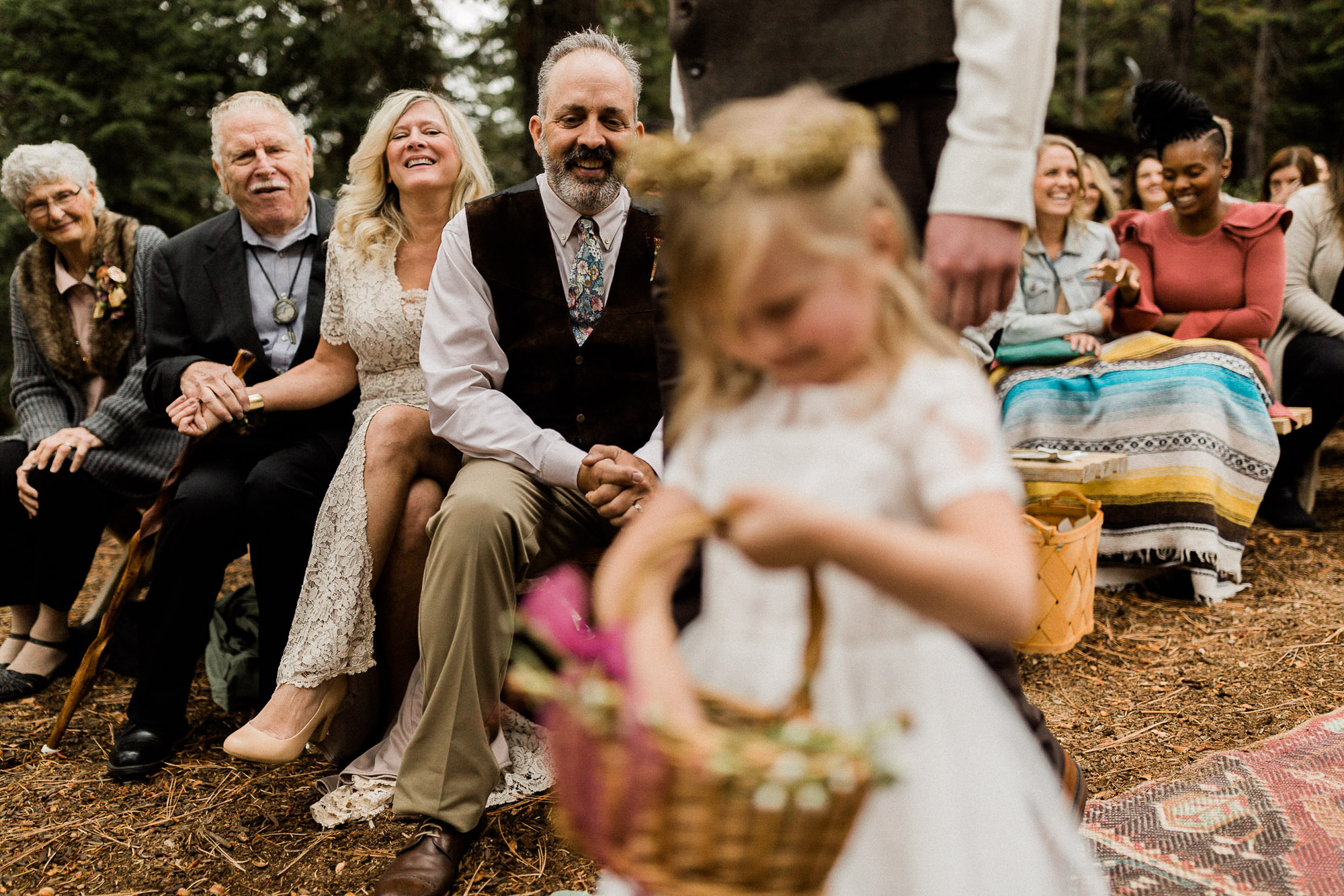 grandparents smile as flower girl walks down the aisle at Skyliner Lodge