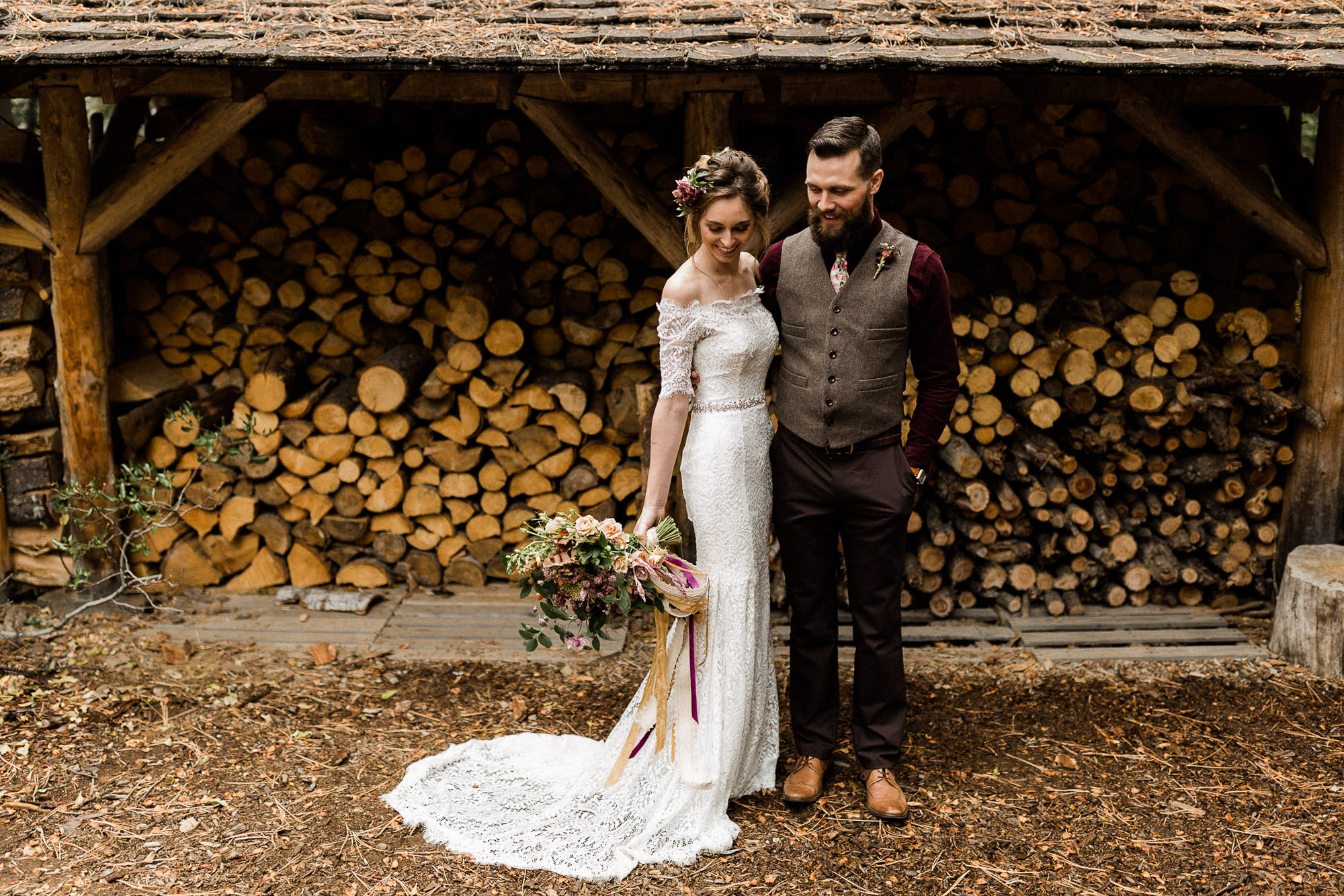 Bride and groom pose for portraits in front of firewood shed at Skyliner Lodge