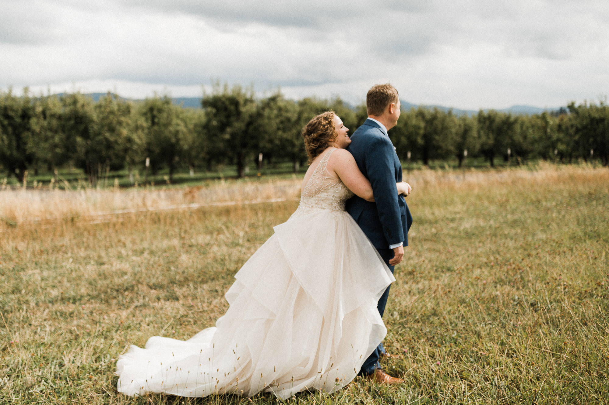 The bride squeezes the groom from behind before the "first look" at Mt. View Orchards.