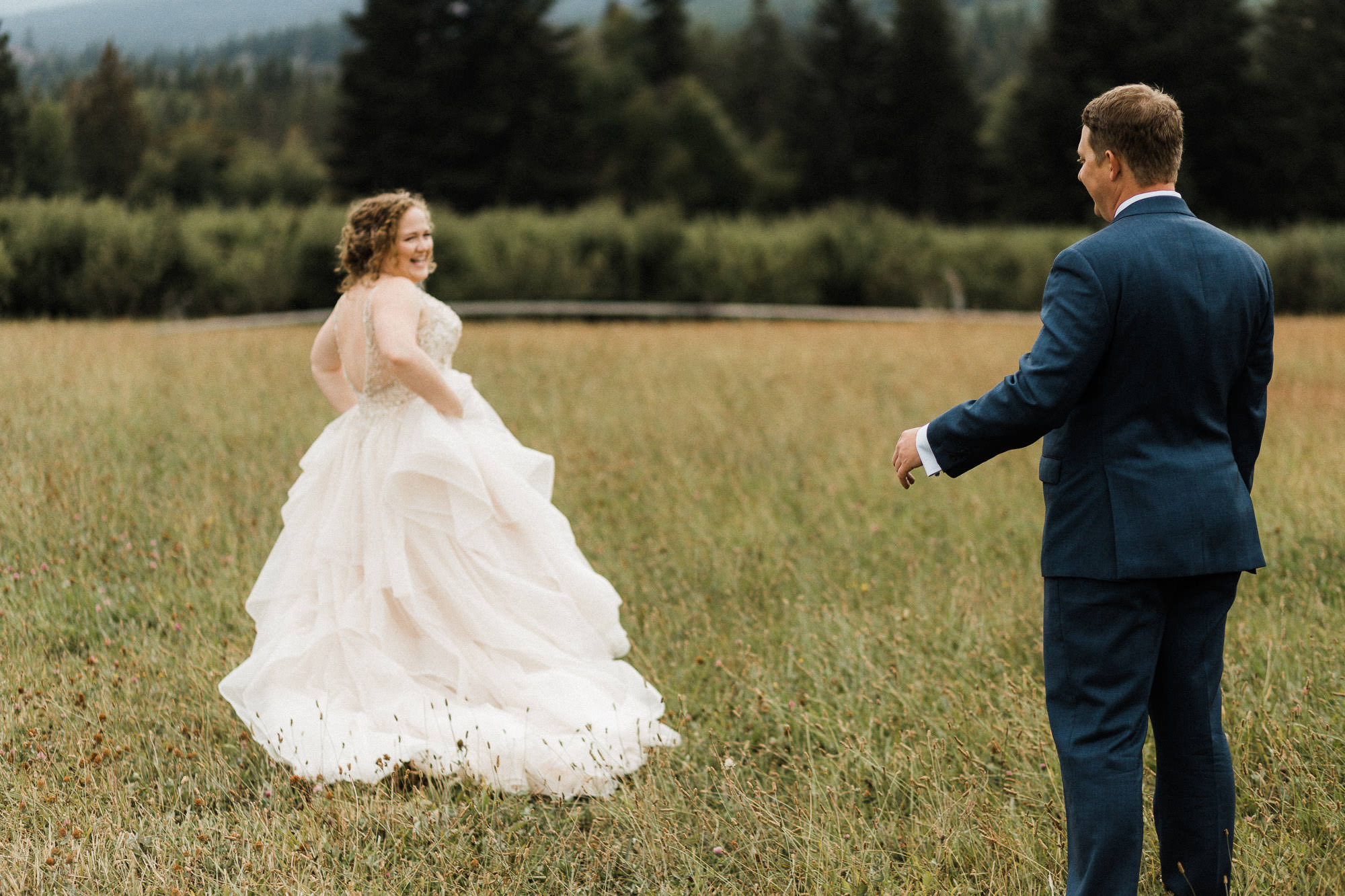 The bride shows off the back of her dress to the groom at Mt. View Orchards in Mt Hood, Oregon.
