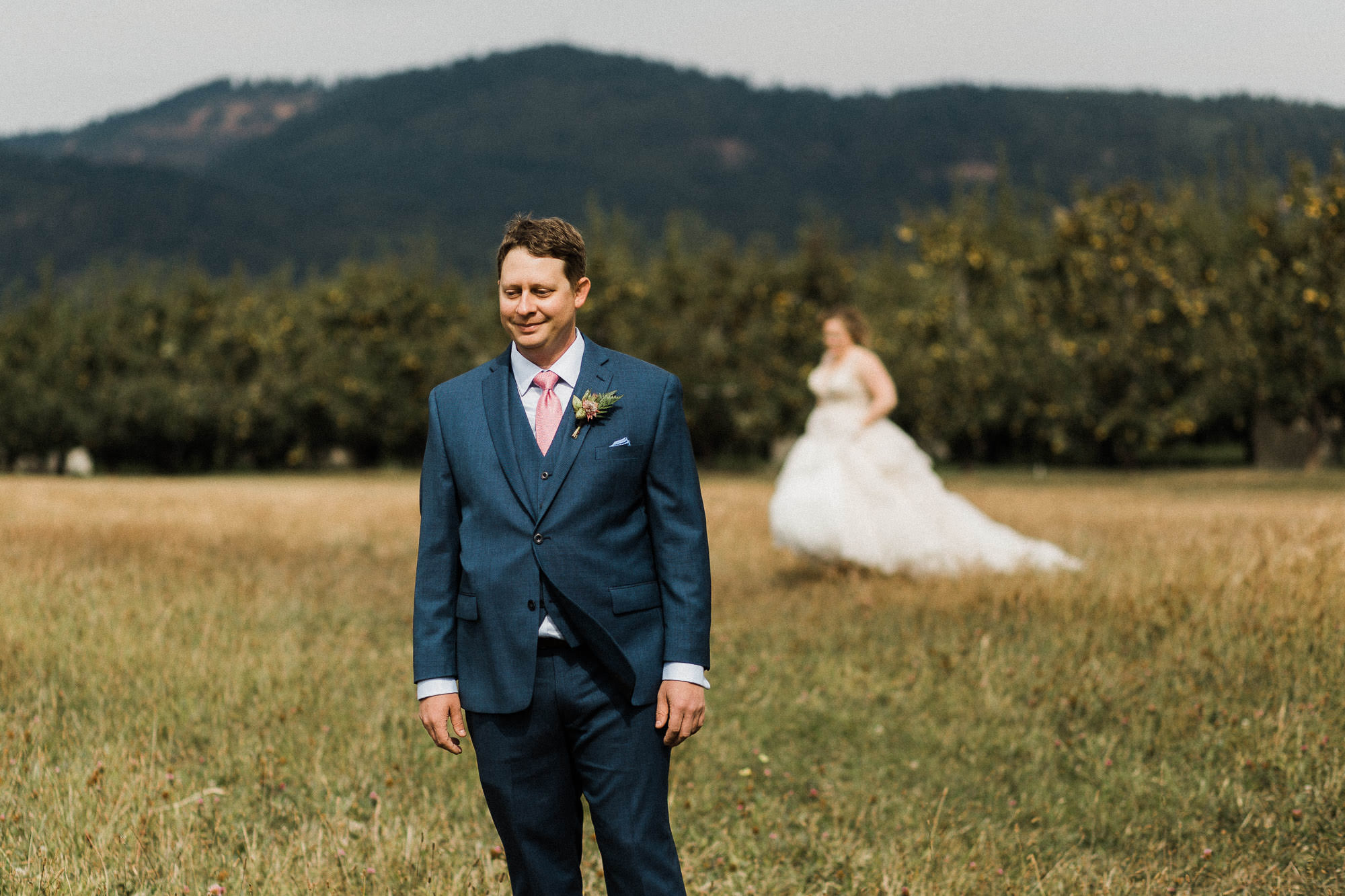 The groom waits for the bride to approach for a "first look" at Mt. View Orchards.