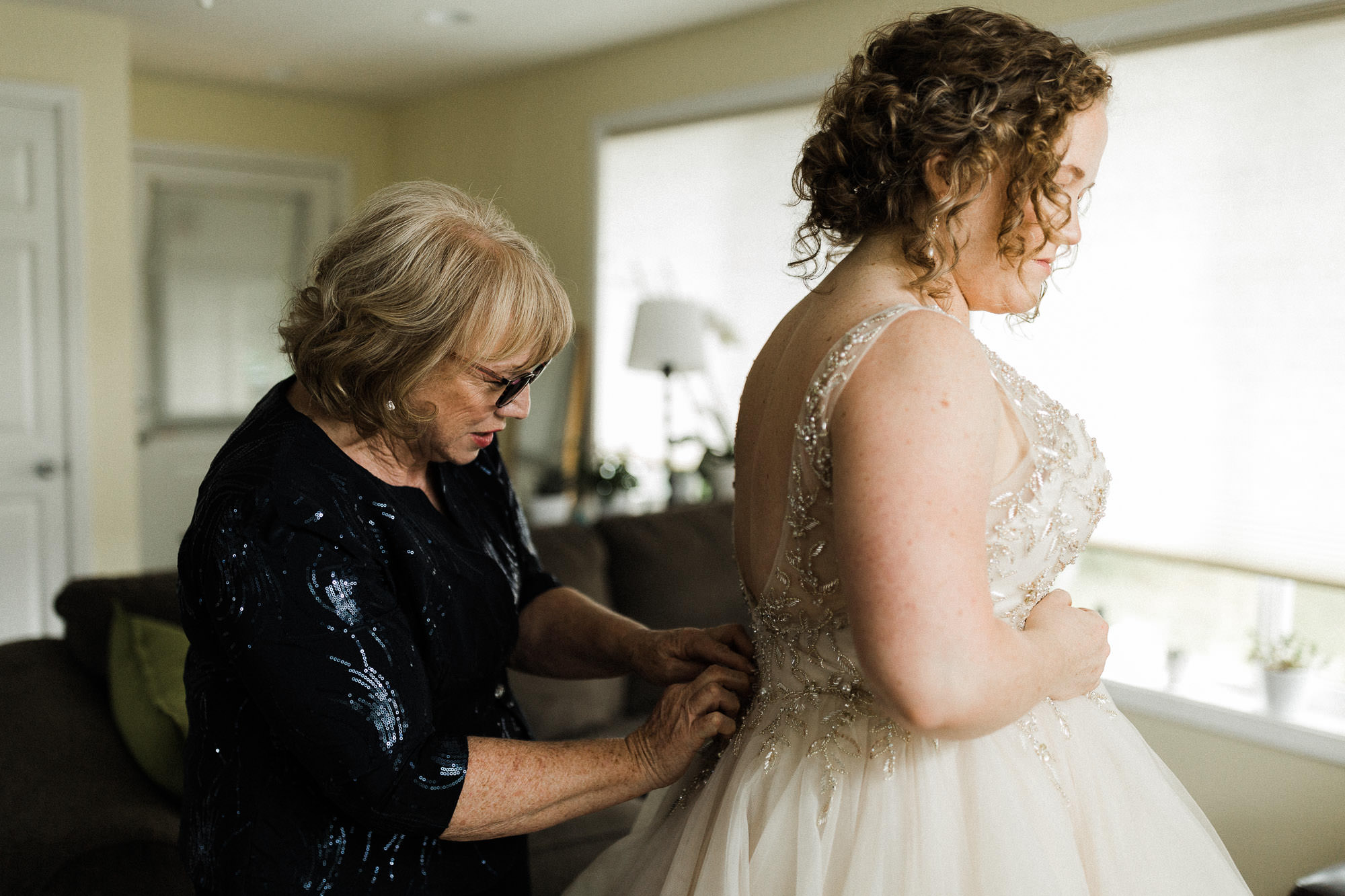 The bride's mother buttons up the bride's wedding dress in Mt. Hood, Oregon.
