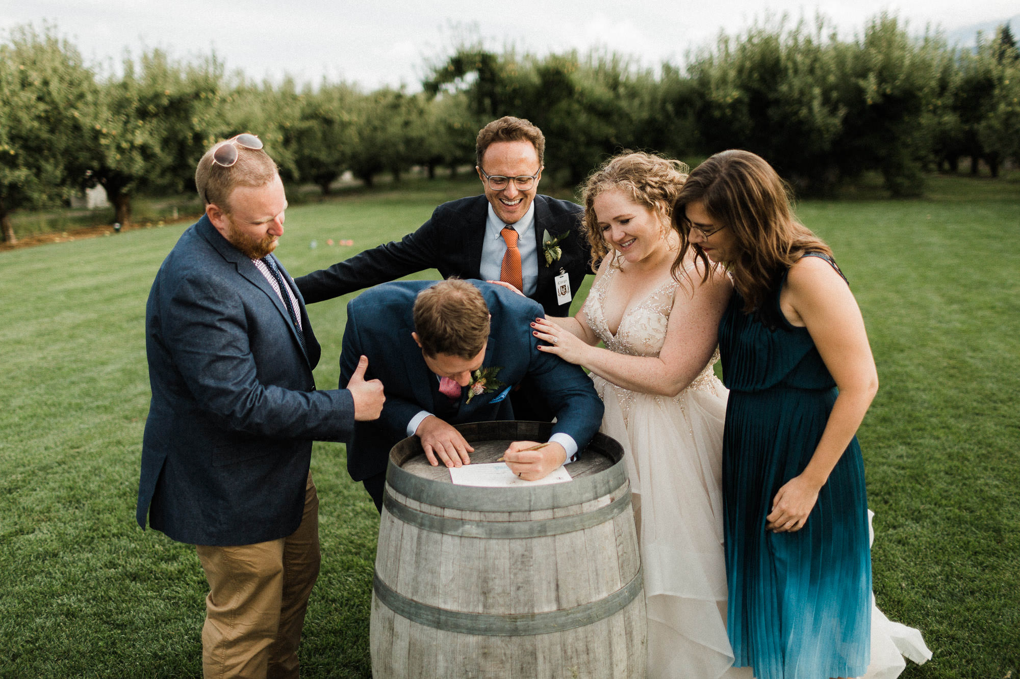 The bride, groom, officiant, and witnesses sign the marriage license at Mt. View Orchards.