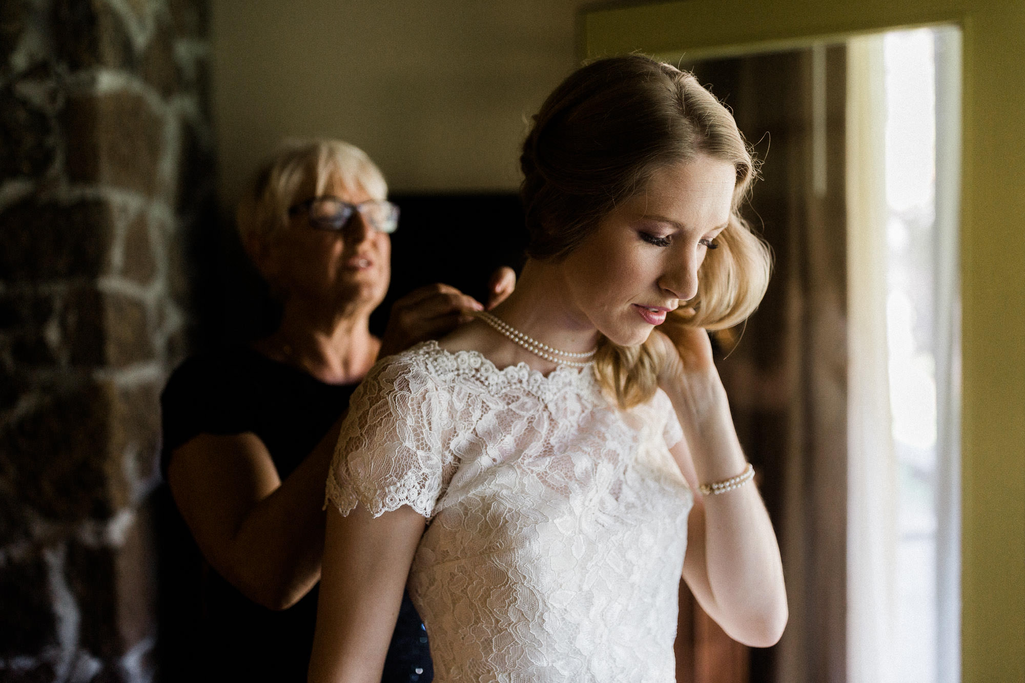 The mother of the bride helps the bride put on a necklace at Sunriver Resort.