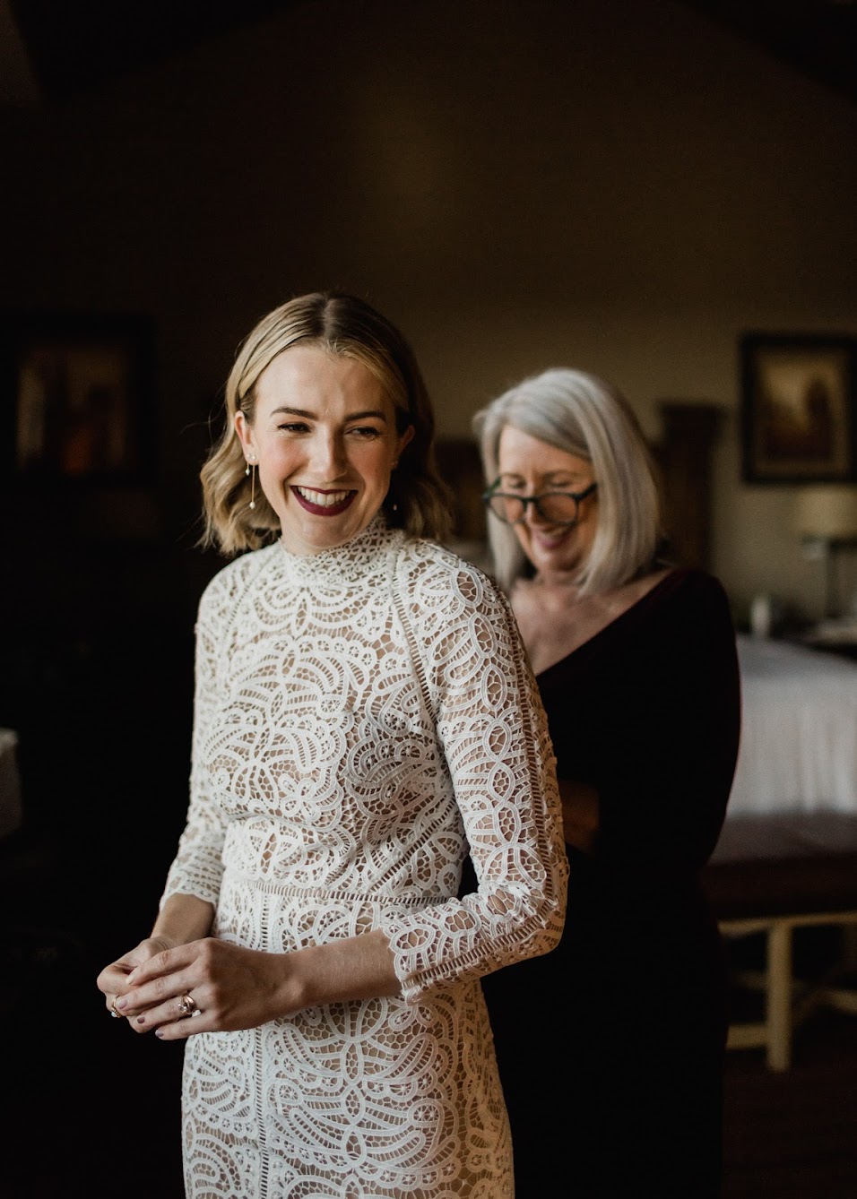 Mother of the bride buttons up the back of the bride’s sleeved wedding dress