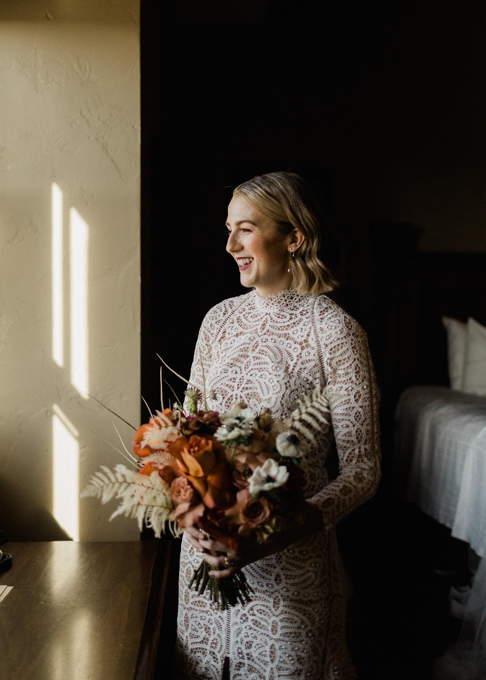 The bride laughing as she holds her color bridal bouquet.