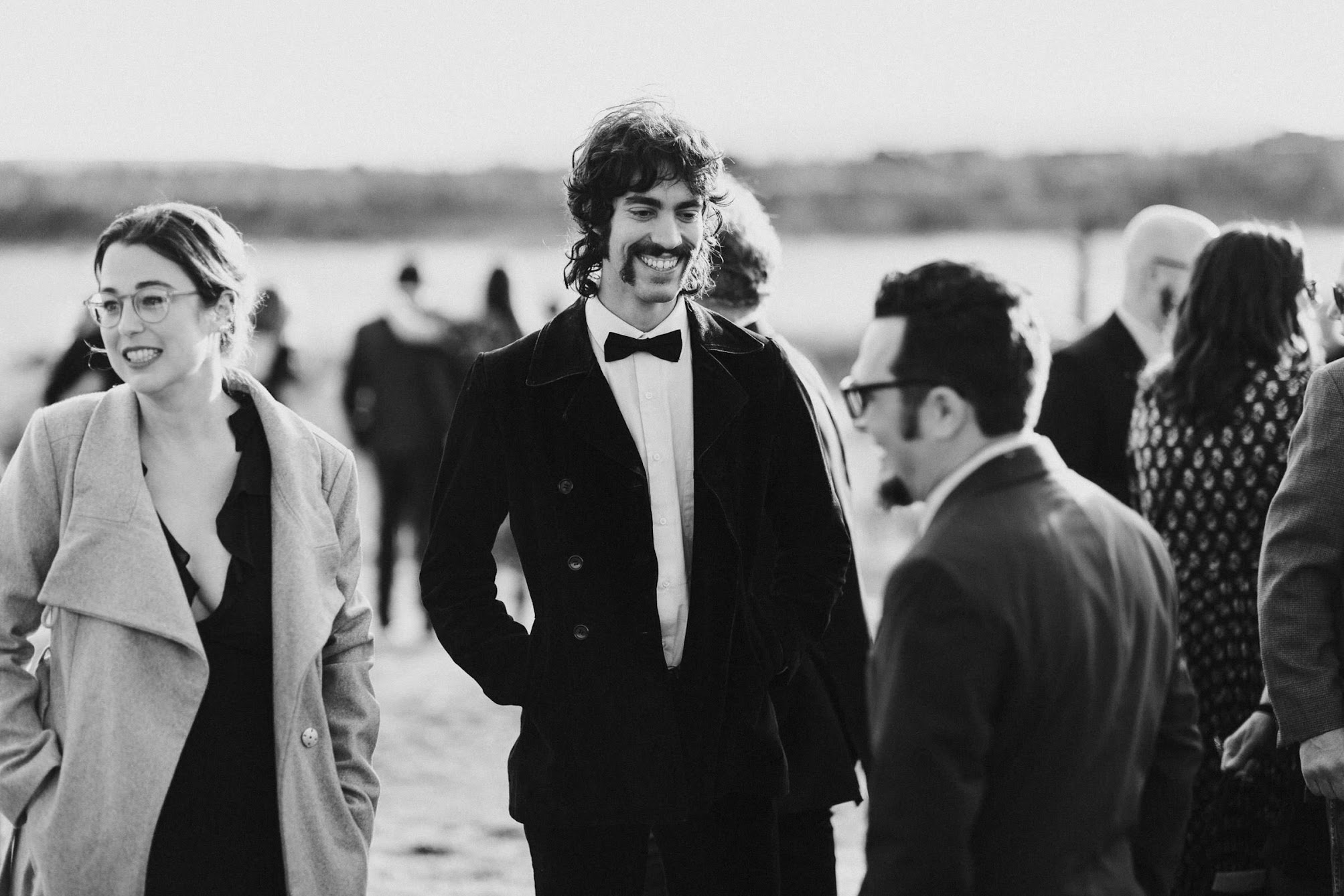Guests standing around in their jackets, suits, and bowties. Talking with each other while they wait for the ceremony to start