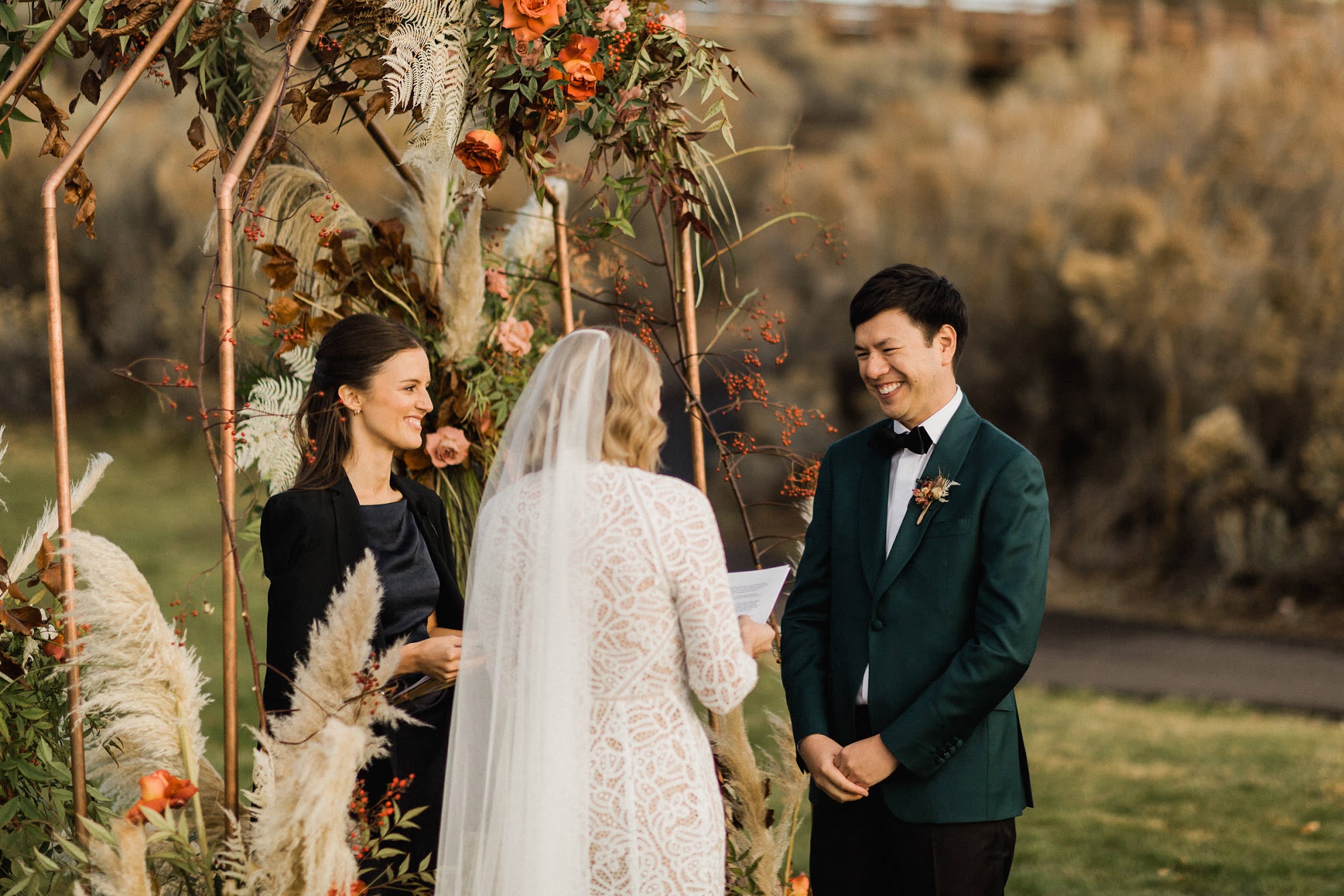 The bride read her vows to the groom. The groom is looking at her smiling. 