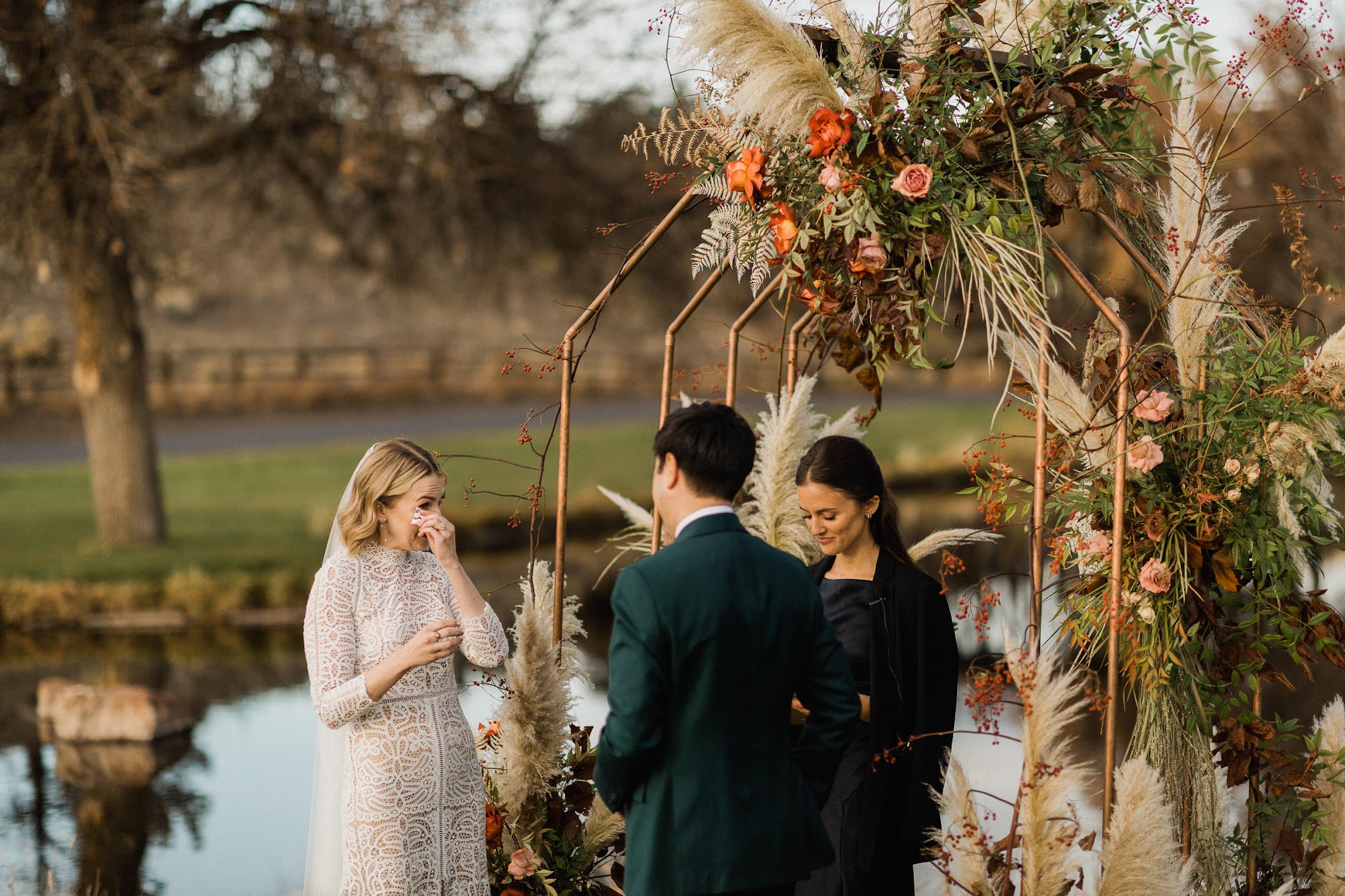 The bride crying and wiping away tears while she listens to the grooms vows to her.