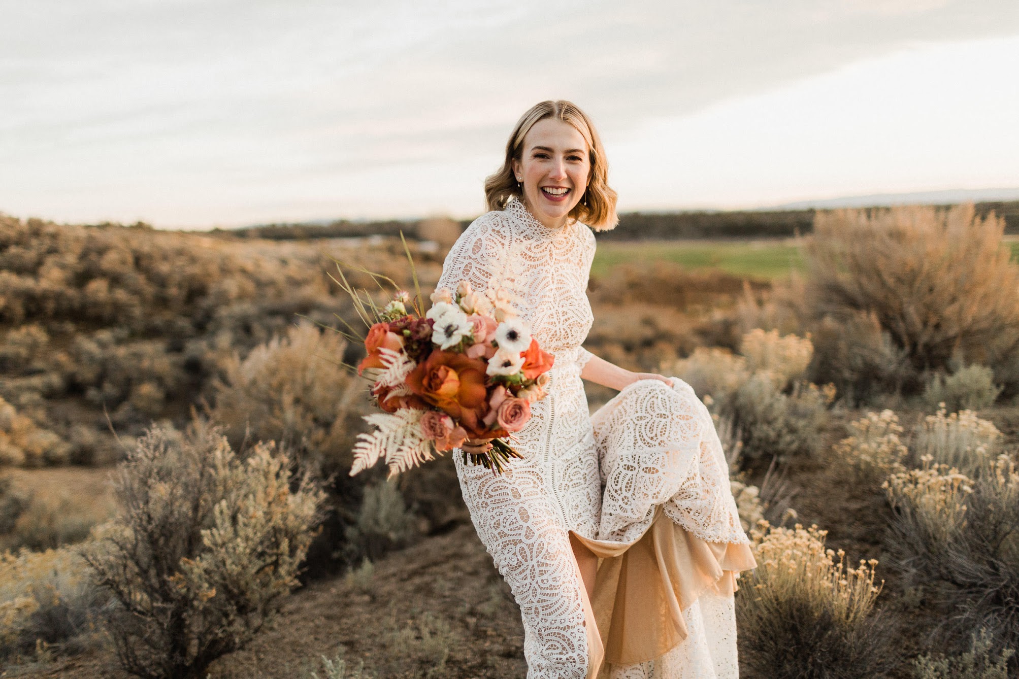 The bride holding her dress with one hand and her bridal boutique in the other with a big smile!