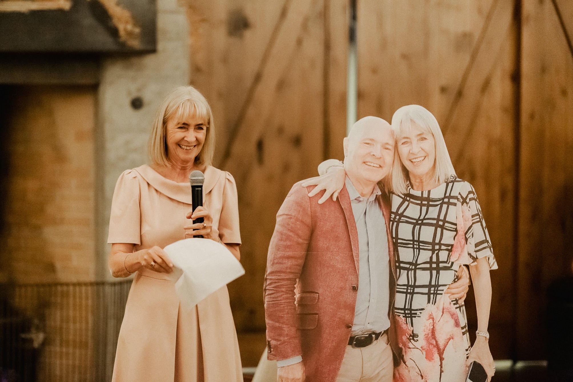 Mother of the bride standing next to a cut out of her and the father of the bride.