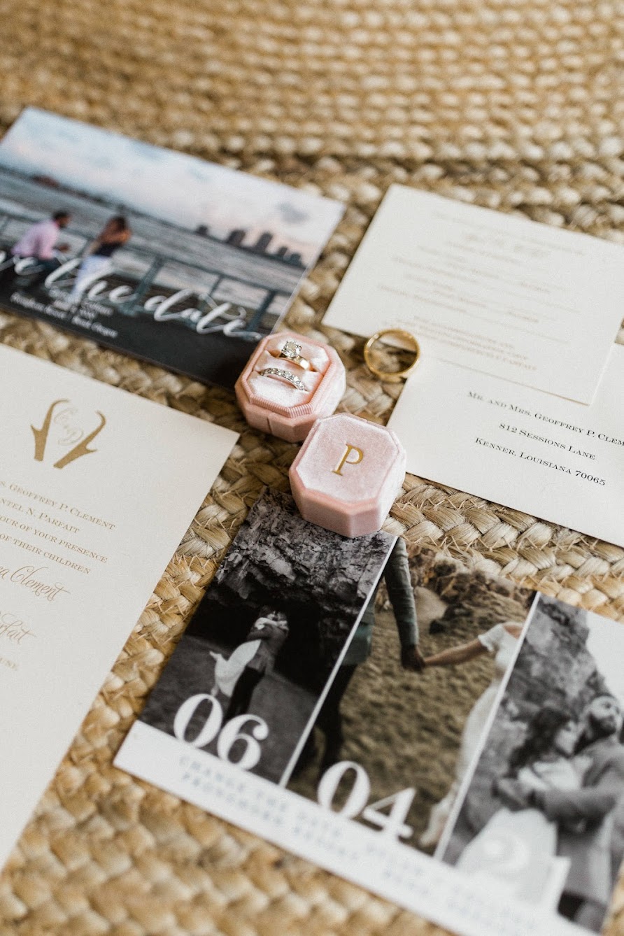 pink velvet ring box with the letter "P" in gold, sitting on top of save the dates and wedding invites.