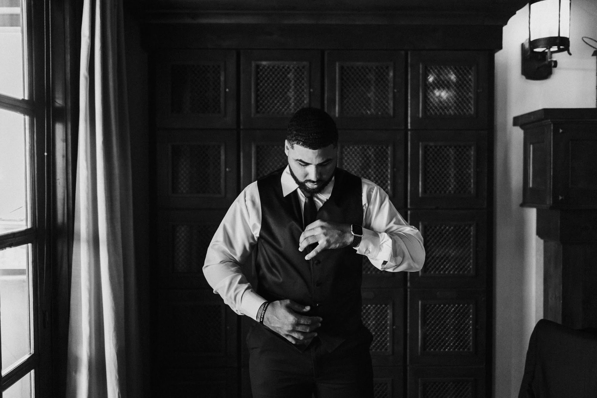 The groom getting ready, fixing his tie and vest. 