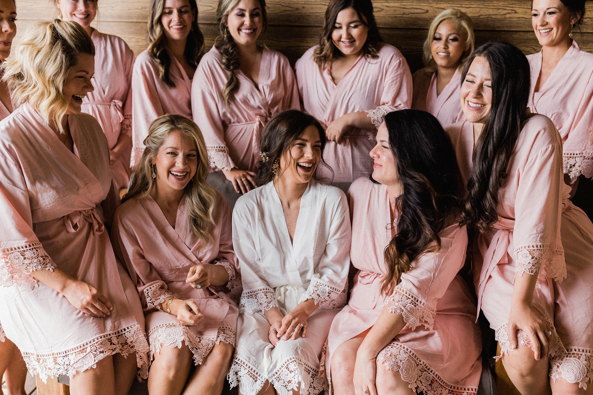 bridesmaids and the bride all in ropes sitting with each other.