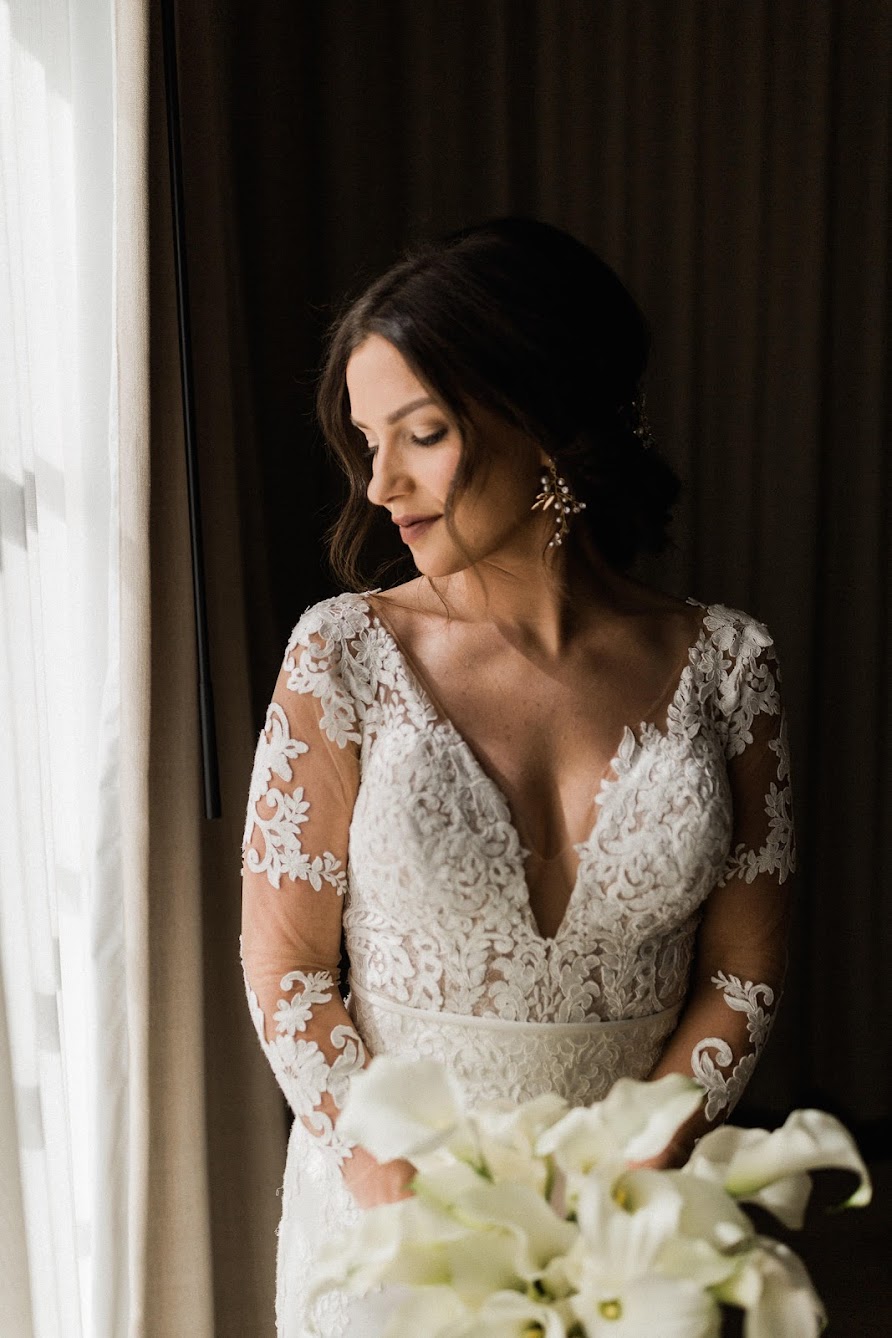 Bride looking over her shoulder, while wearing her lace wedding dress and holding her bouquet.