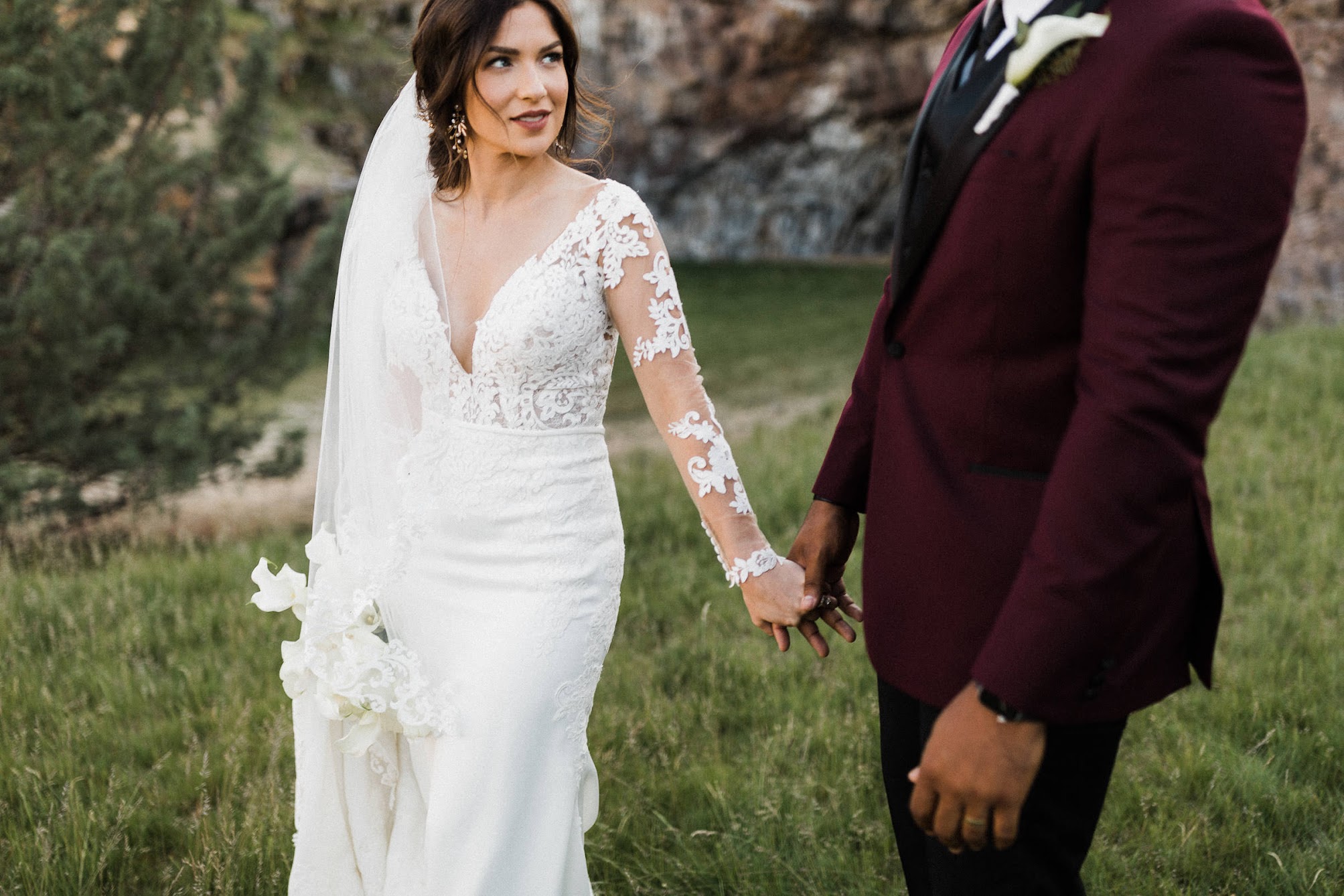 holding hands while walking in a grassy field 