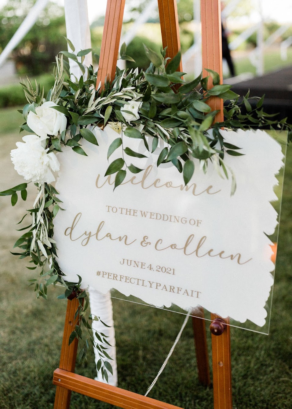 wedding welcome sign that is acrylic and has flowers on it. 