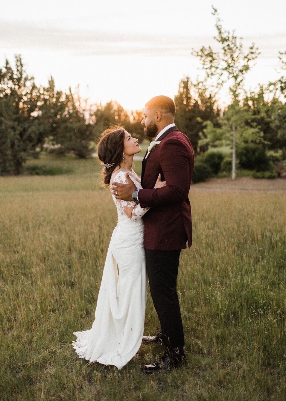 the couple standing in a grassy field taking sunset photos 