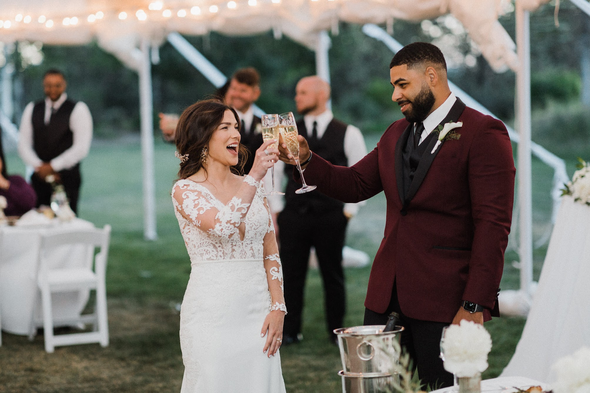 The couple under a tent, holding champagne glasses