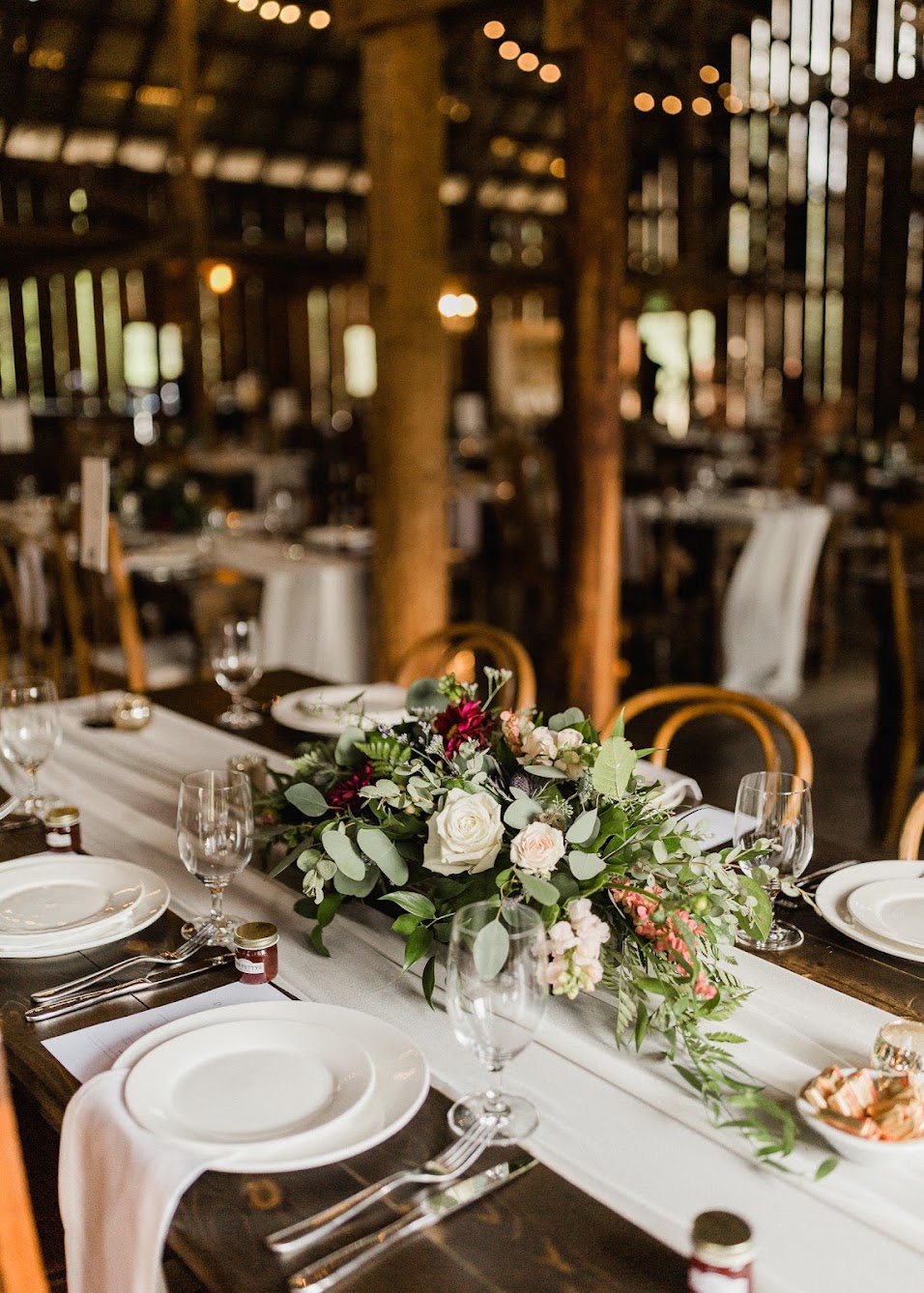 Guests tables with simple decor. A table runner and florals in the middle. 