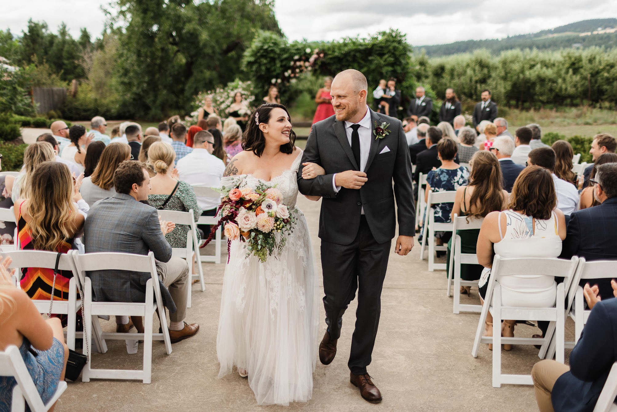 Bride and groom looking at each other smiling as they walk together down the aisle.