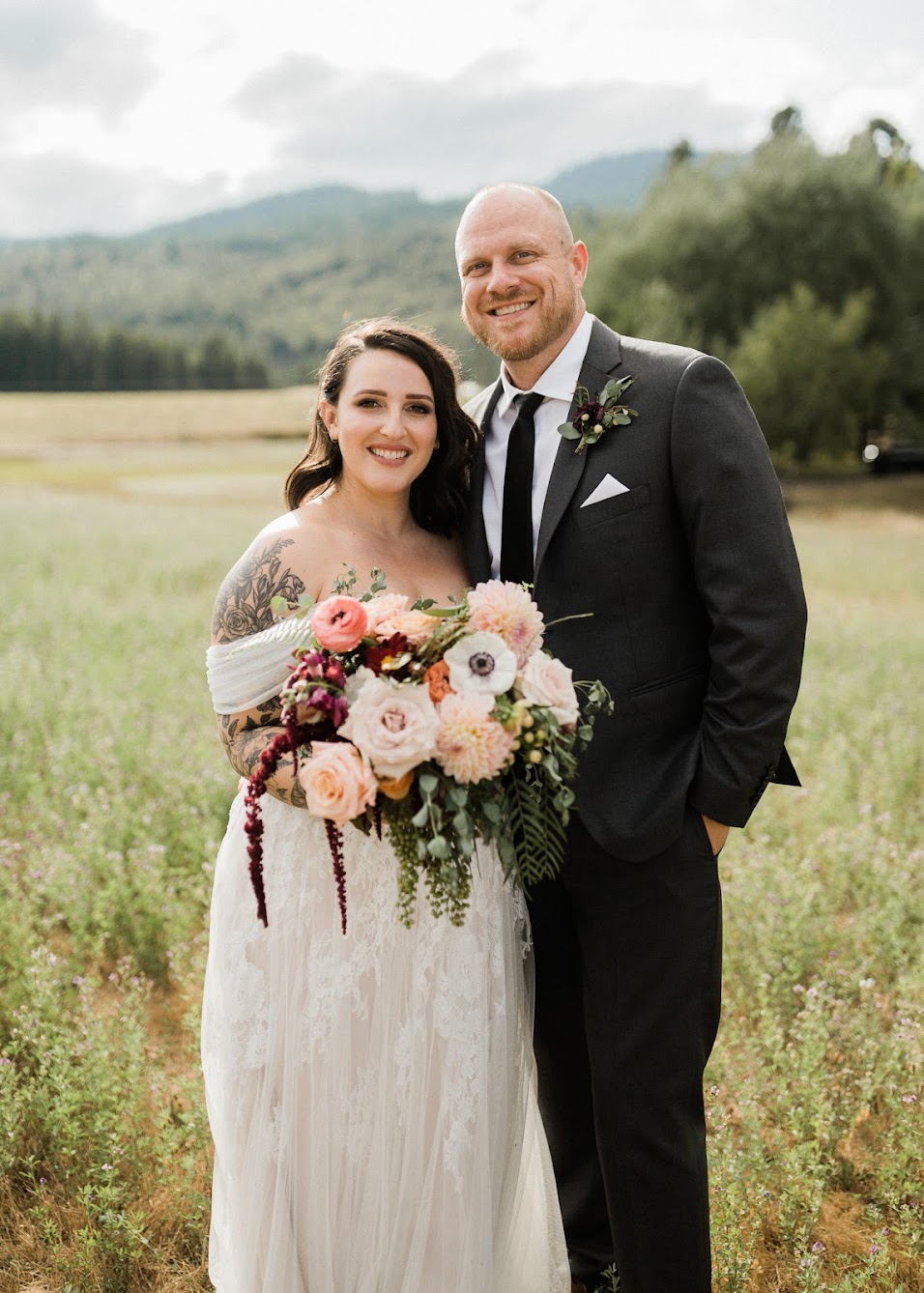 The bride and groom look into the camera with big smiles on. 