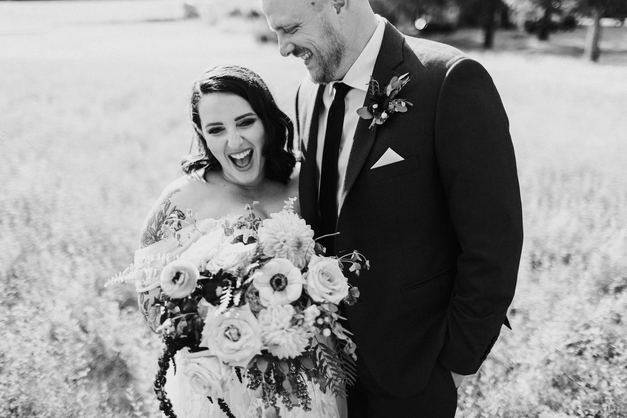 The groom looks at his bride smiling while the bride is laughing.