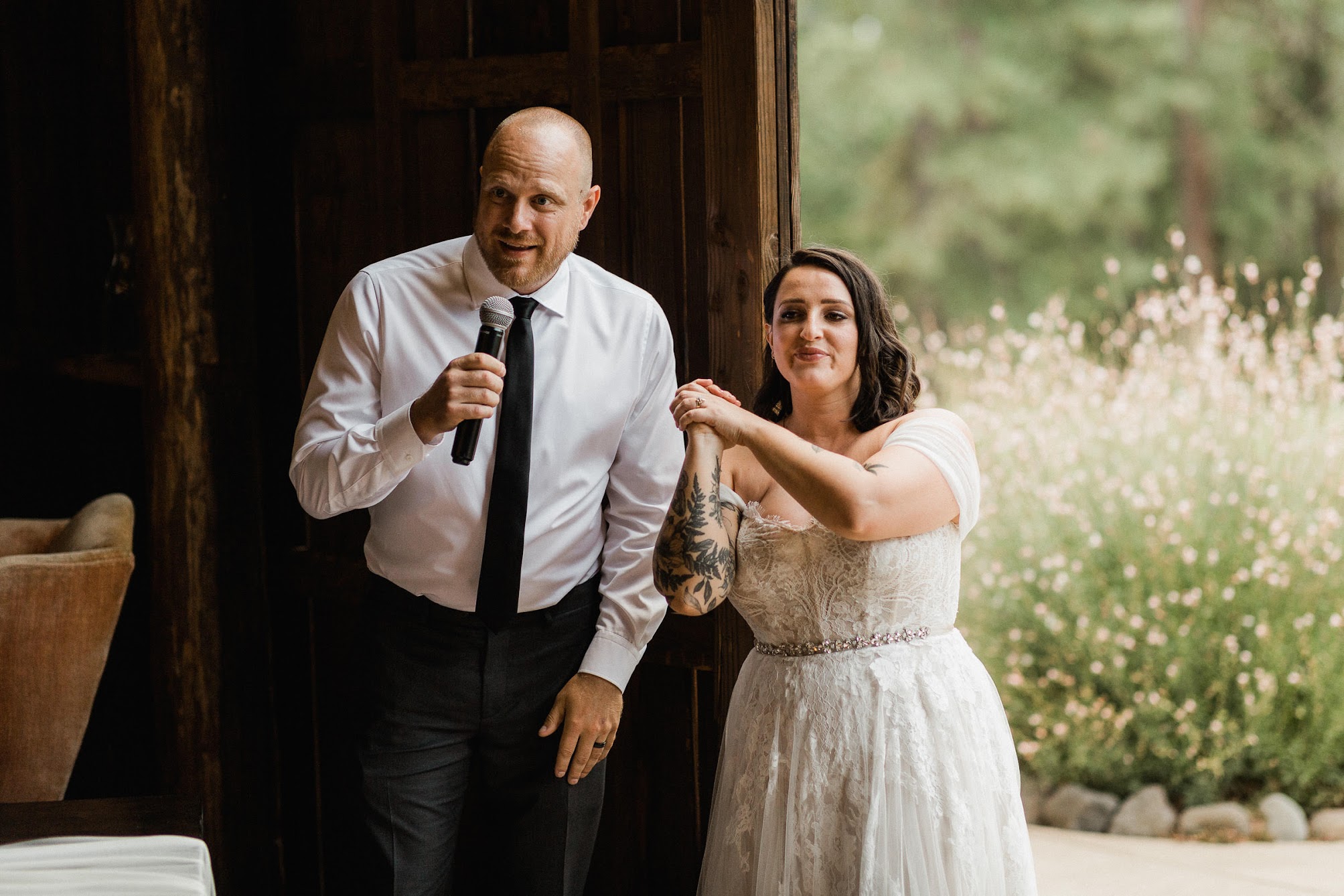 The couple standing in from of their guests with a microphone saying thank you to everyone who has come to celebrate with them. 