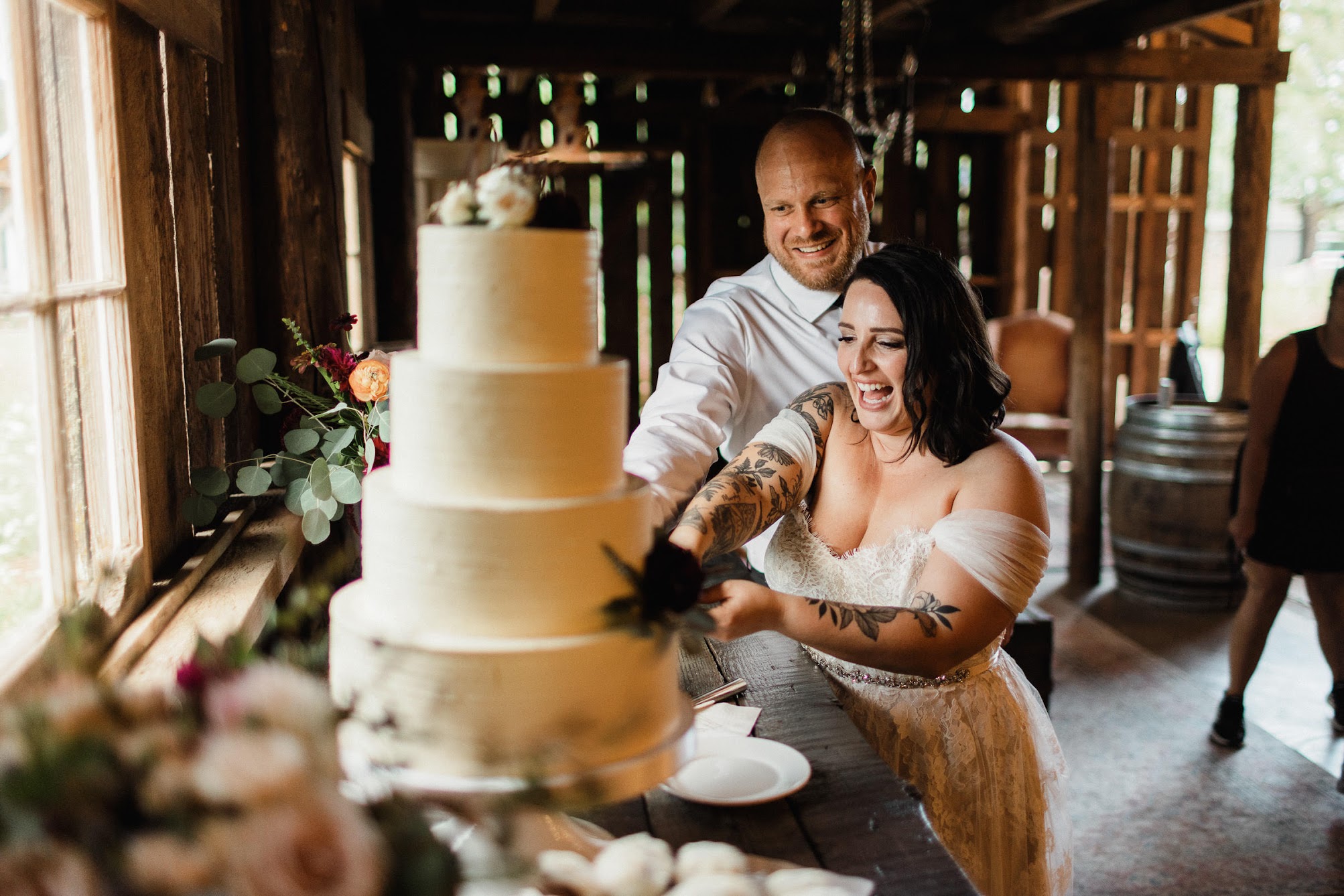 A white four-tier wedding cake, with groupings of florals on the top and bottom tier.