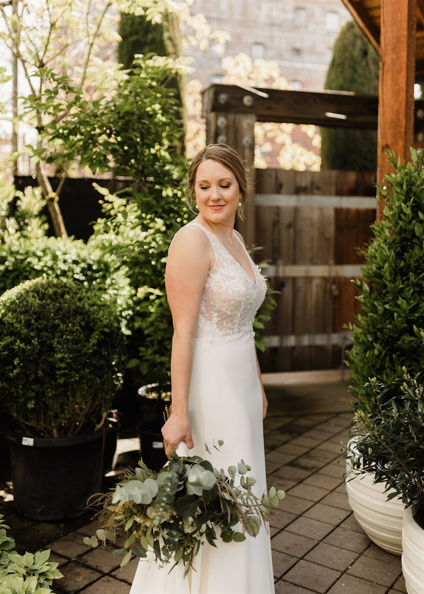 the bride standing in a garden looking over her shoulder 