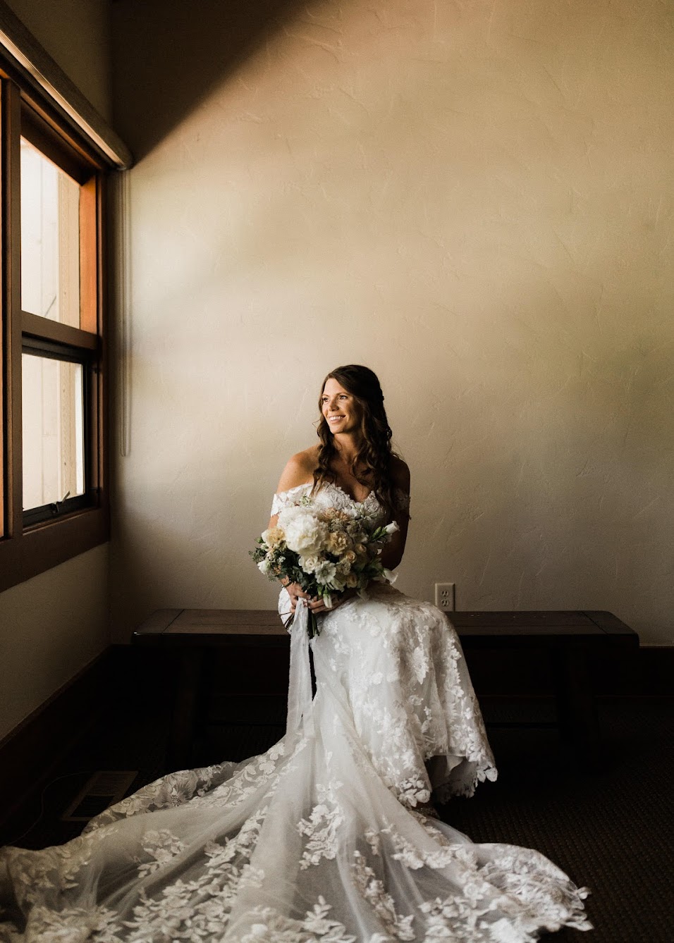 Bride sitting down looking out the window, holding her bouquet.